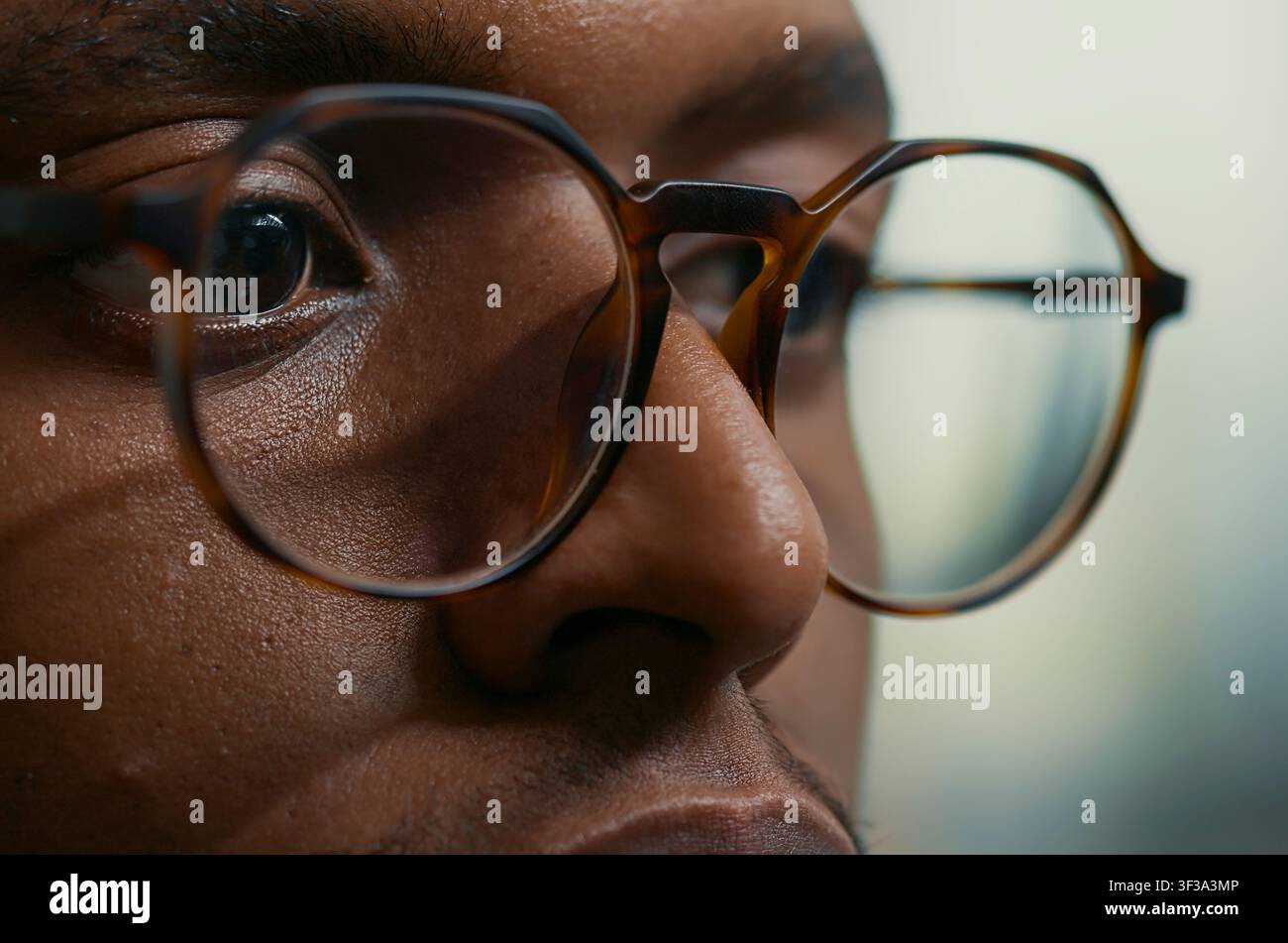 Concentrated close portrait with african american database developer with glasses working concentrated reviewing computer screen at a computer screen, showing software development focus, coding. Stock Photo