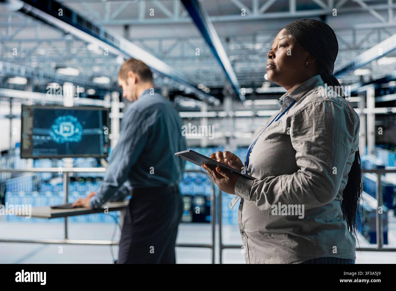 Teamworking data center system administrators review code for AI automation scripts. Server room colleagues run artificial intelligence assisted diagnostics on equipment for predictive error detection Stock Photo