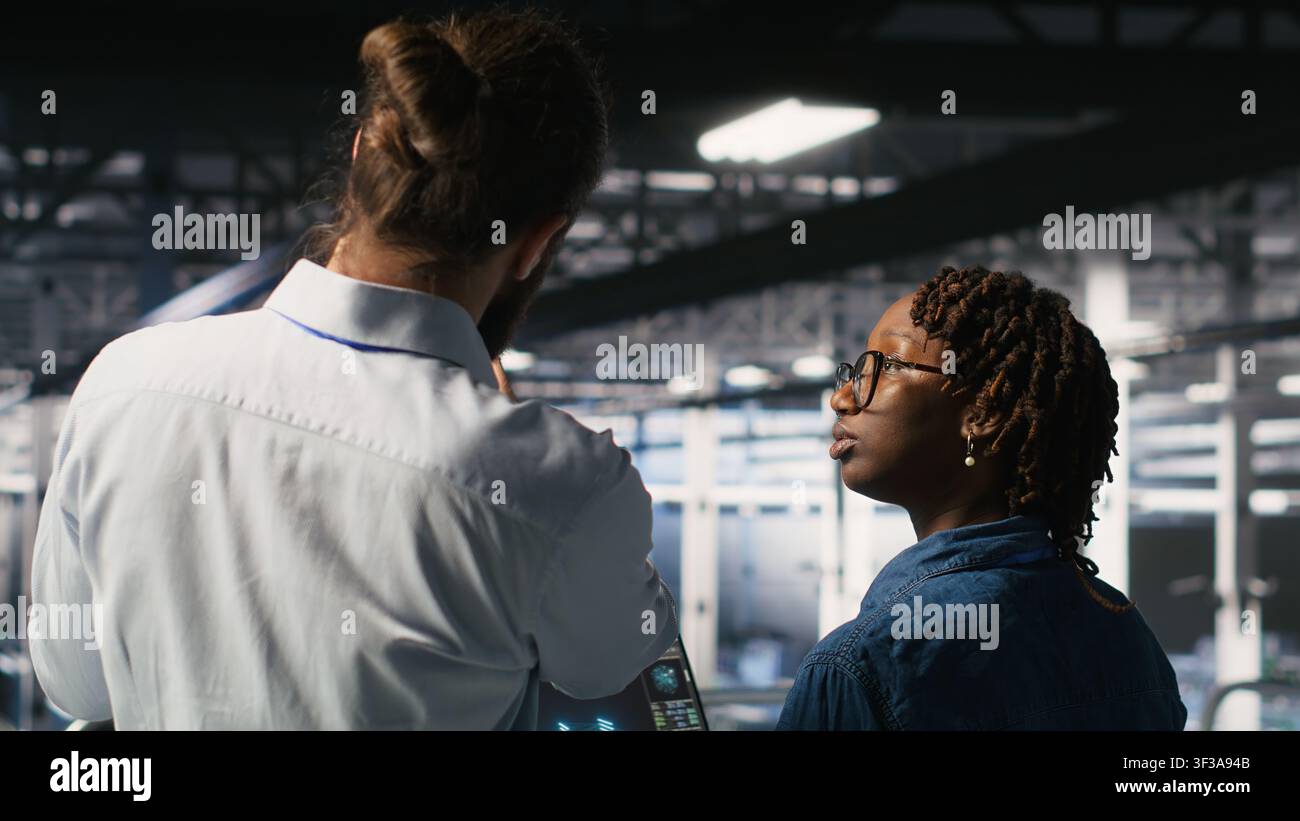 Data center manager overseeing work done by admin using neural network AI LLM visualization. Server farm team leader and worker overseeing rigs powering machine learning processes Stock Photo