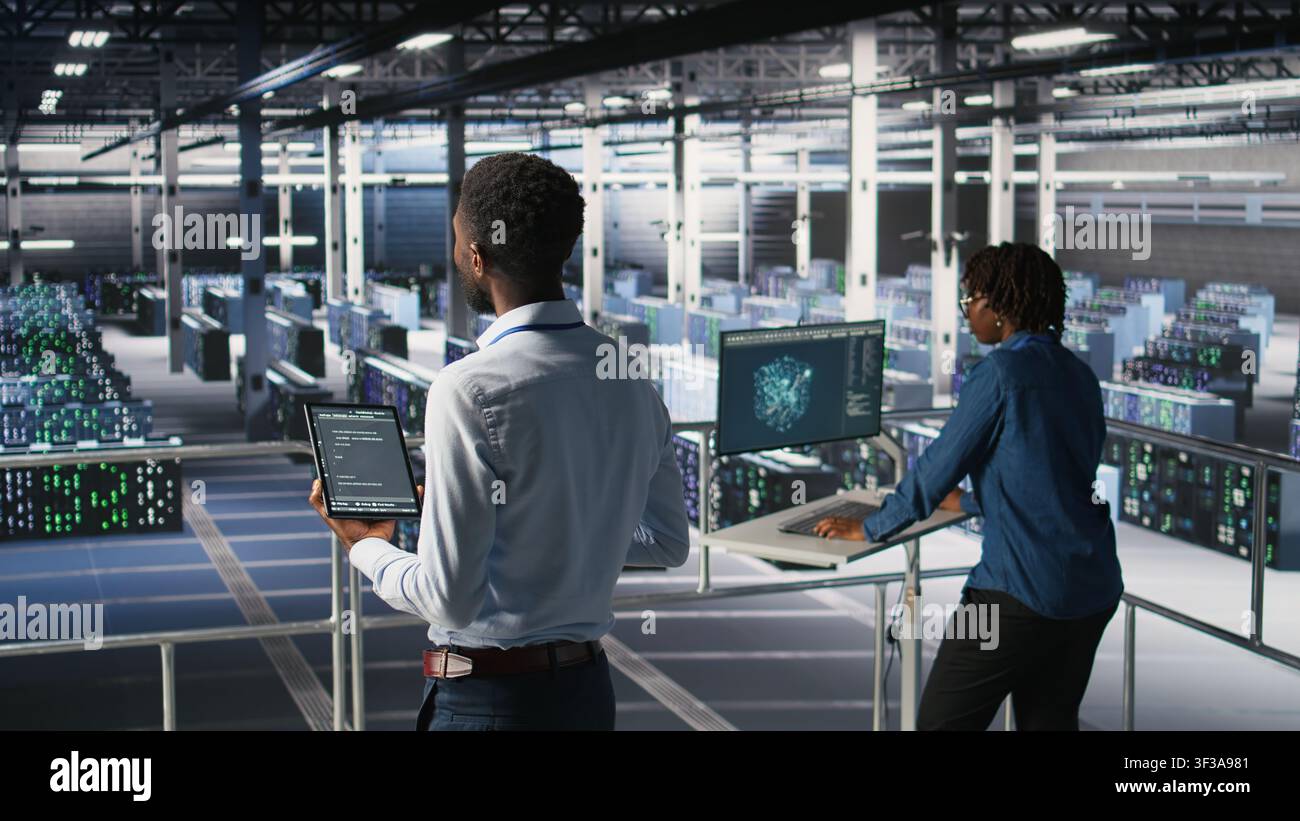 Data center programmers on industrial platform checking lines of code, collaborating on tasks. Server hub IT specialists visualizing large language model architecture using tablet and PC Stock Photo