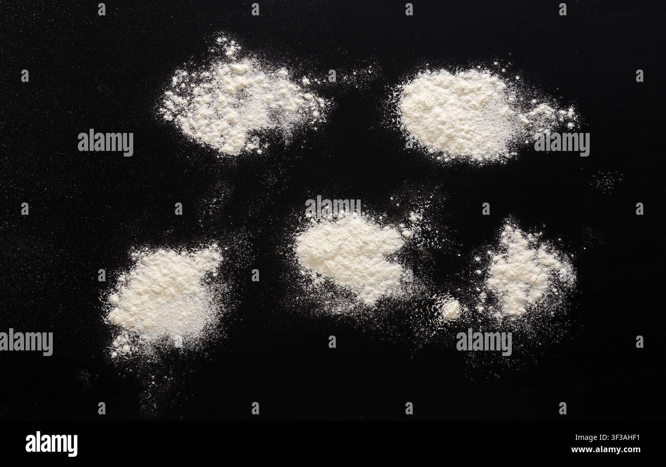 Sprinkled wheat flour splash spots on black background Stock Photo