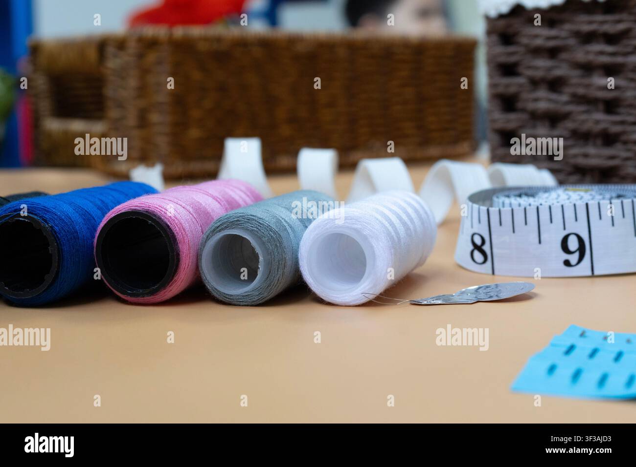 Colorful Sewing Threads Measuring Tape and Needle on Tailor Table Stock Photo
