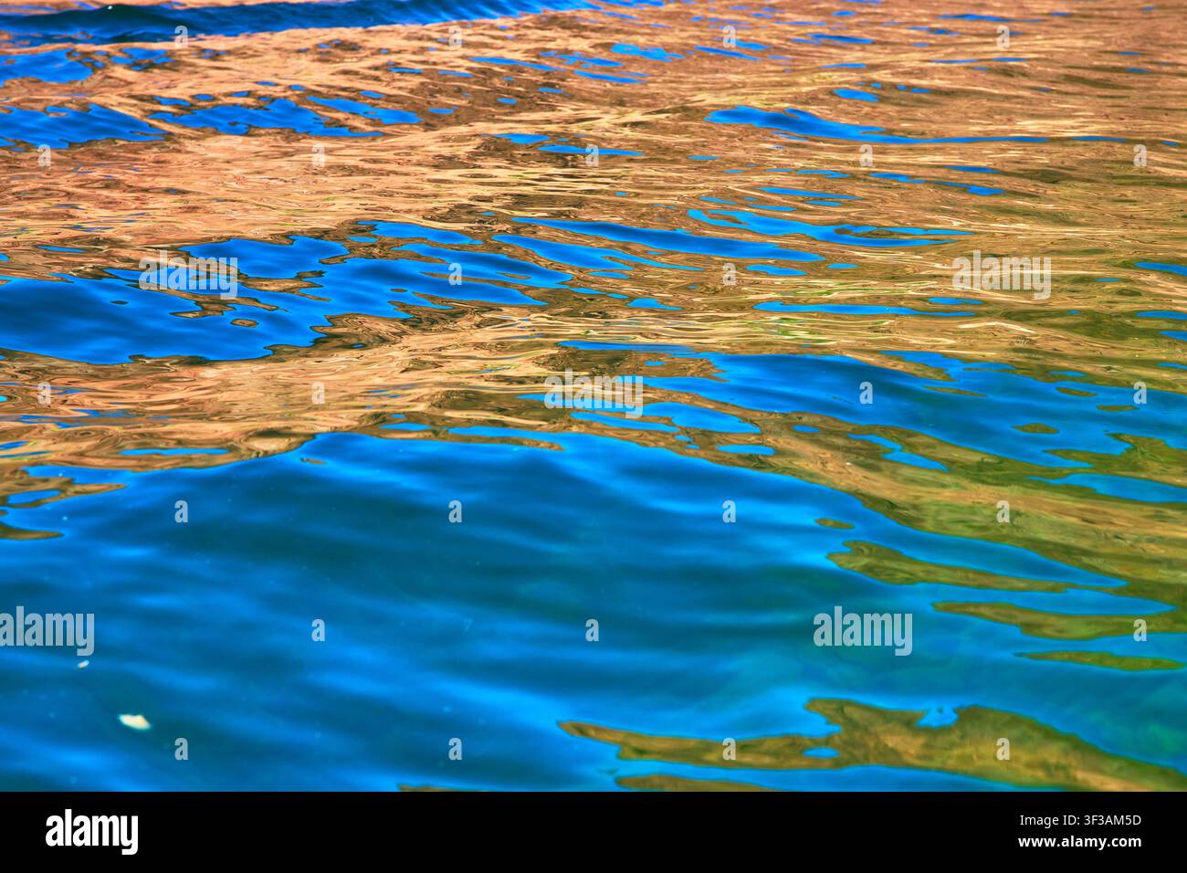 Vivid Water Surface Reflection with Blue and Gold Abstract Patterns Stock Photo
