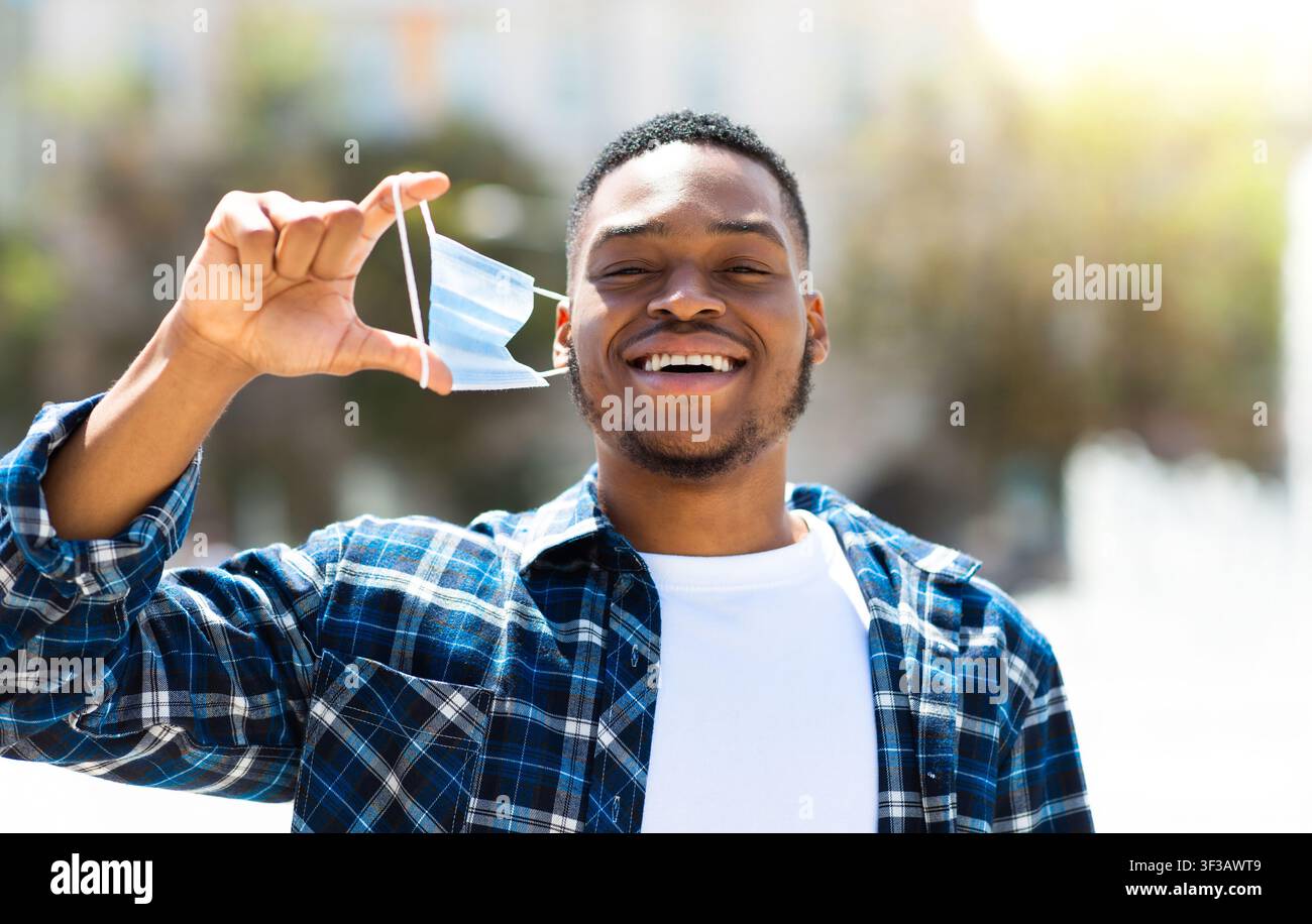 Portrait of happy man taking off mask in the city Stock Photo