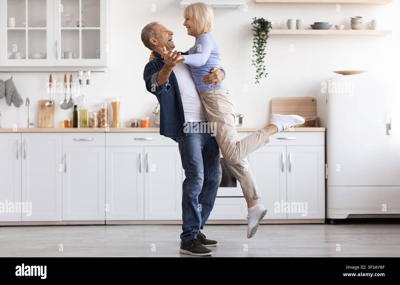 Romantic elderly man and woman dancing at kitchen Stock Photo