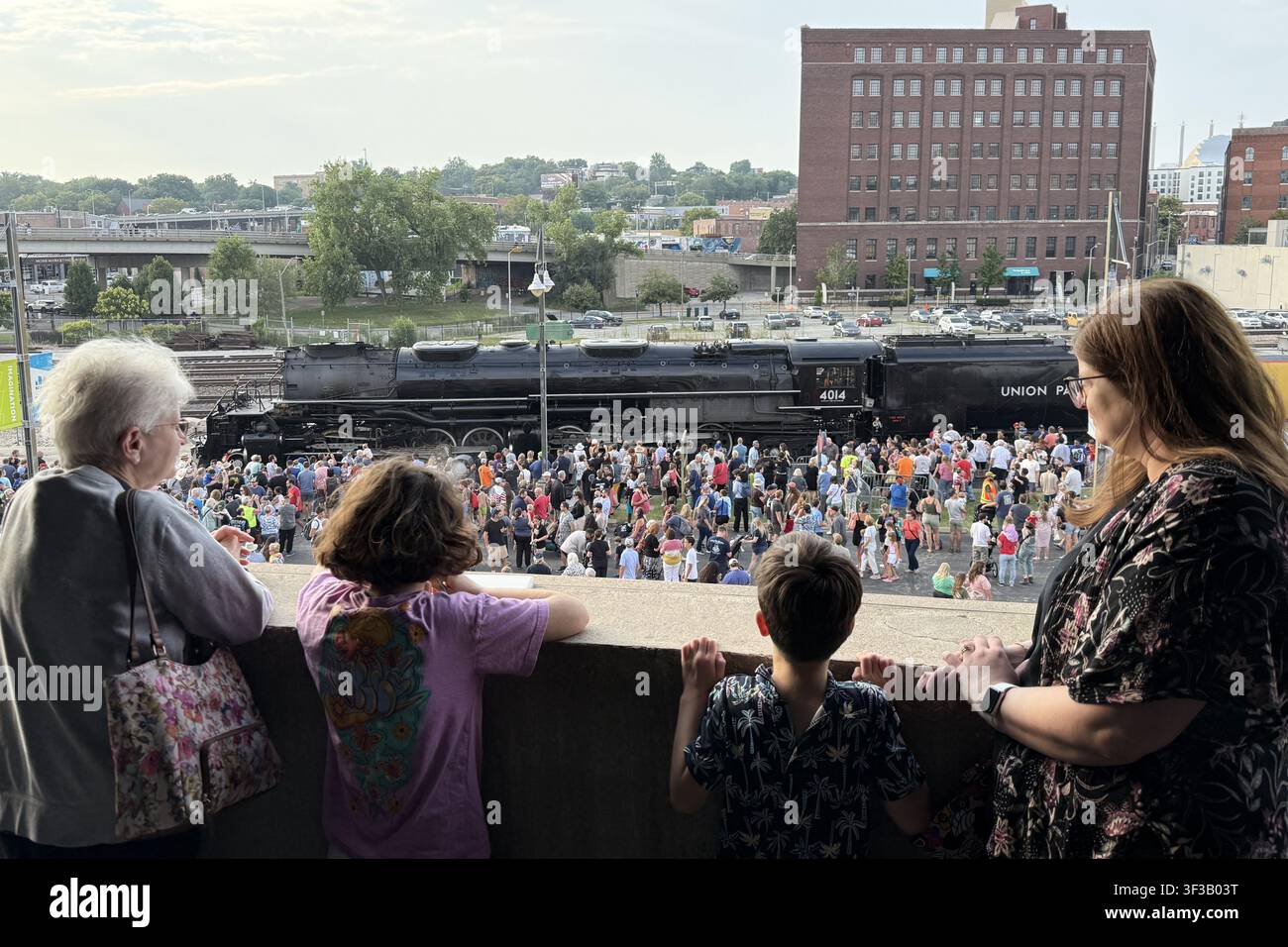 Crowds view Union Pacific "Big Boy" 4014 locomotive at Union Station Kansas City on July 22, 2026, with a family watching from an upper parking level. - Smartphone Captured Stock Image