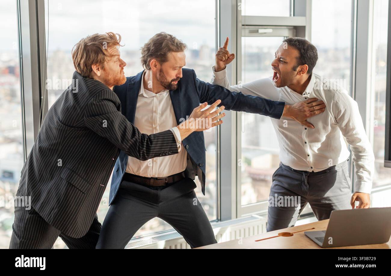 Three Businessmen Involved in Intense Argument in a Modern Office Stock Photo