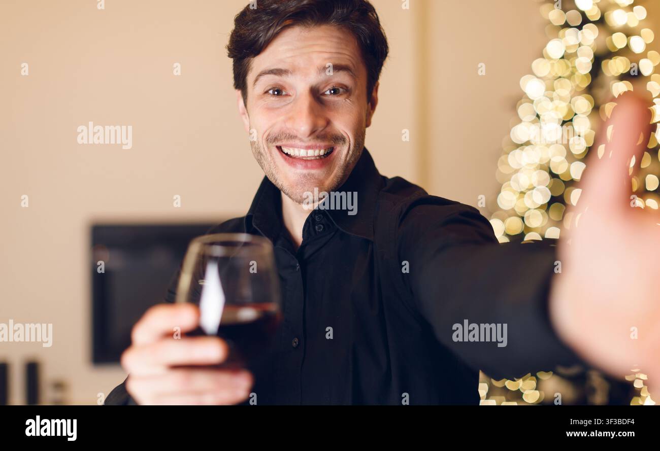 Young man drinking red wine, looking at camera Stock Photo