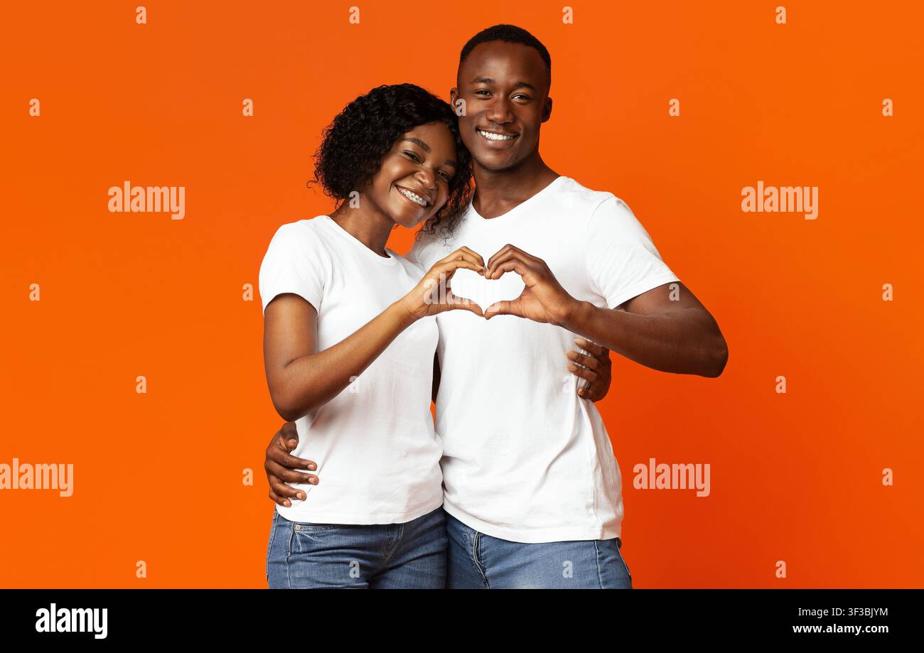 Smiling african lovers making heart shape gesture with hands Stock Photo