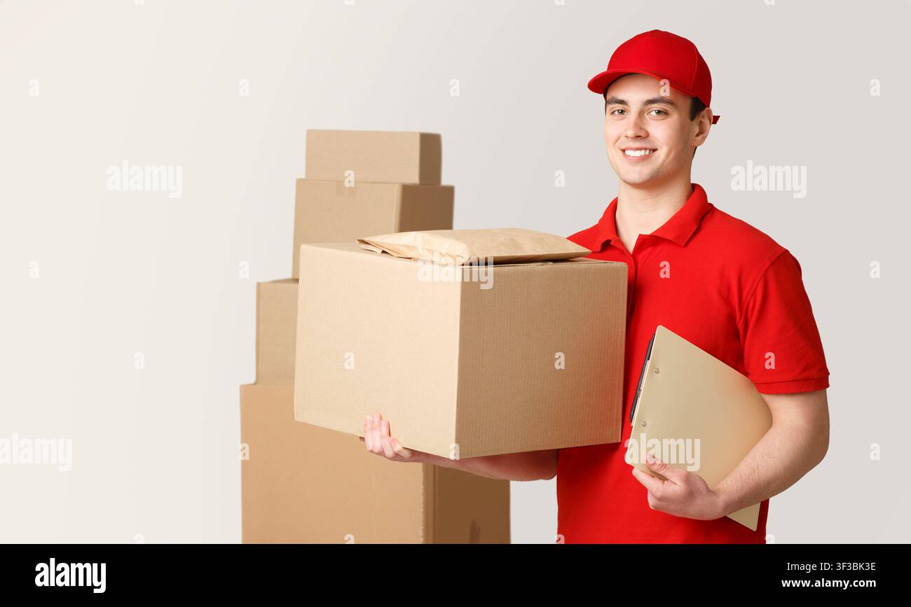 Courier and package in warehouse. Deliveryman holding box and tablet near stack of parcels Stock Photo