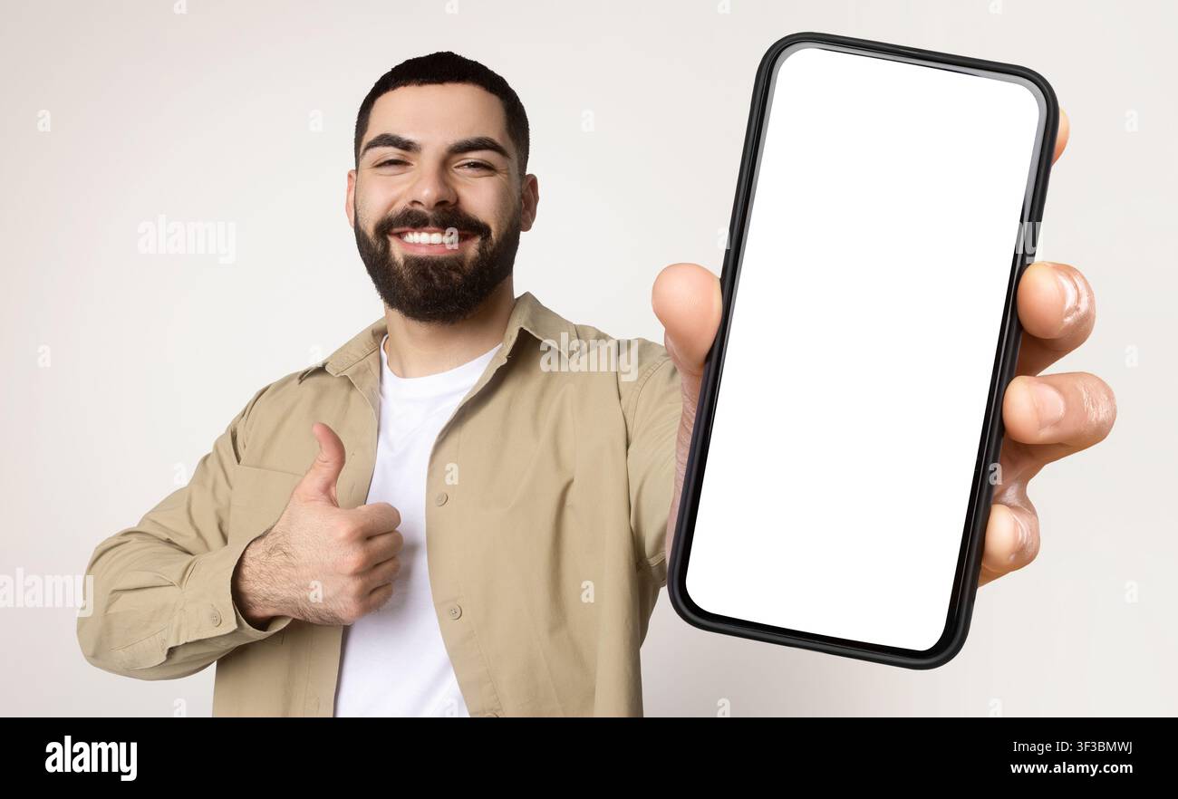 Millennial Man Holding Smart Phone With White Screen Stock Photo