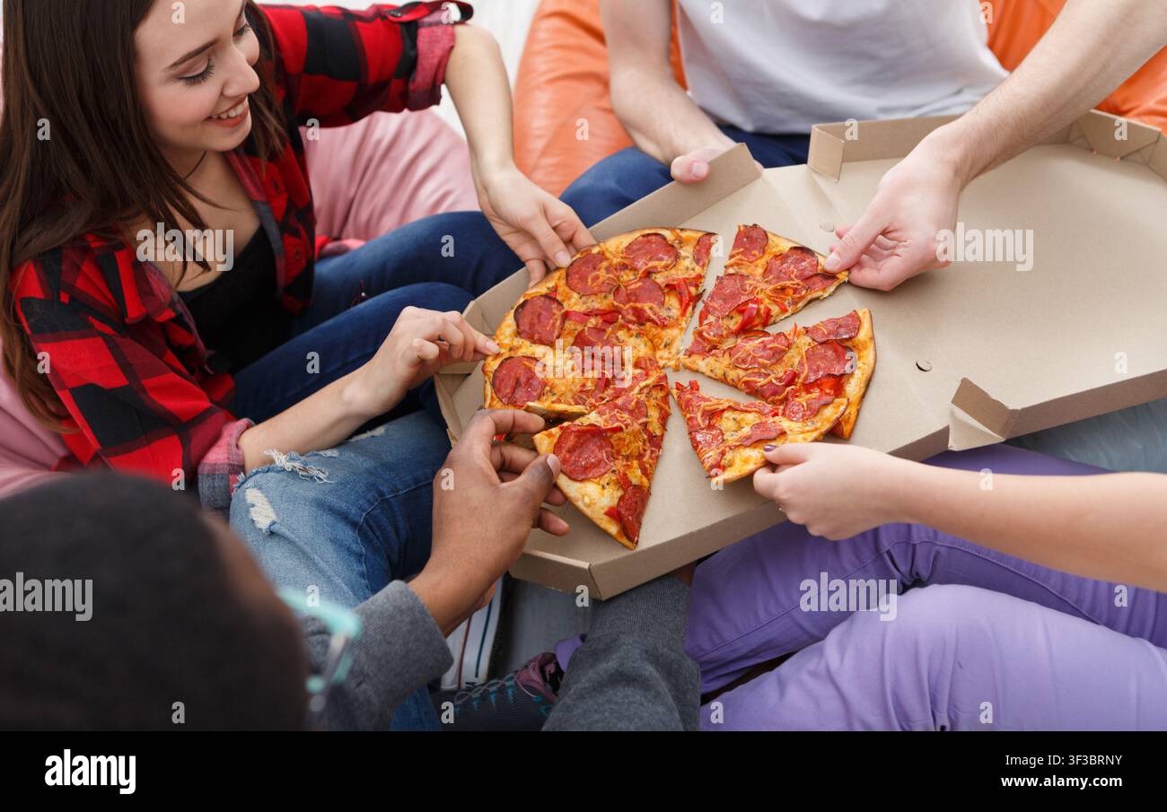 Students sharing pizza at home party Stock Photo