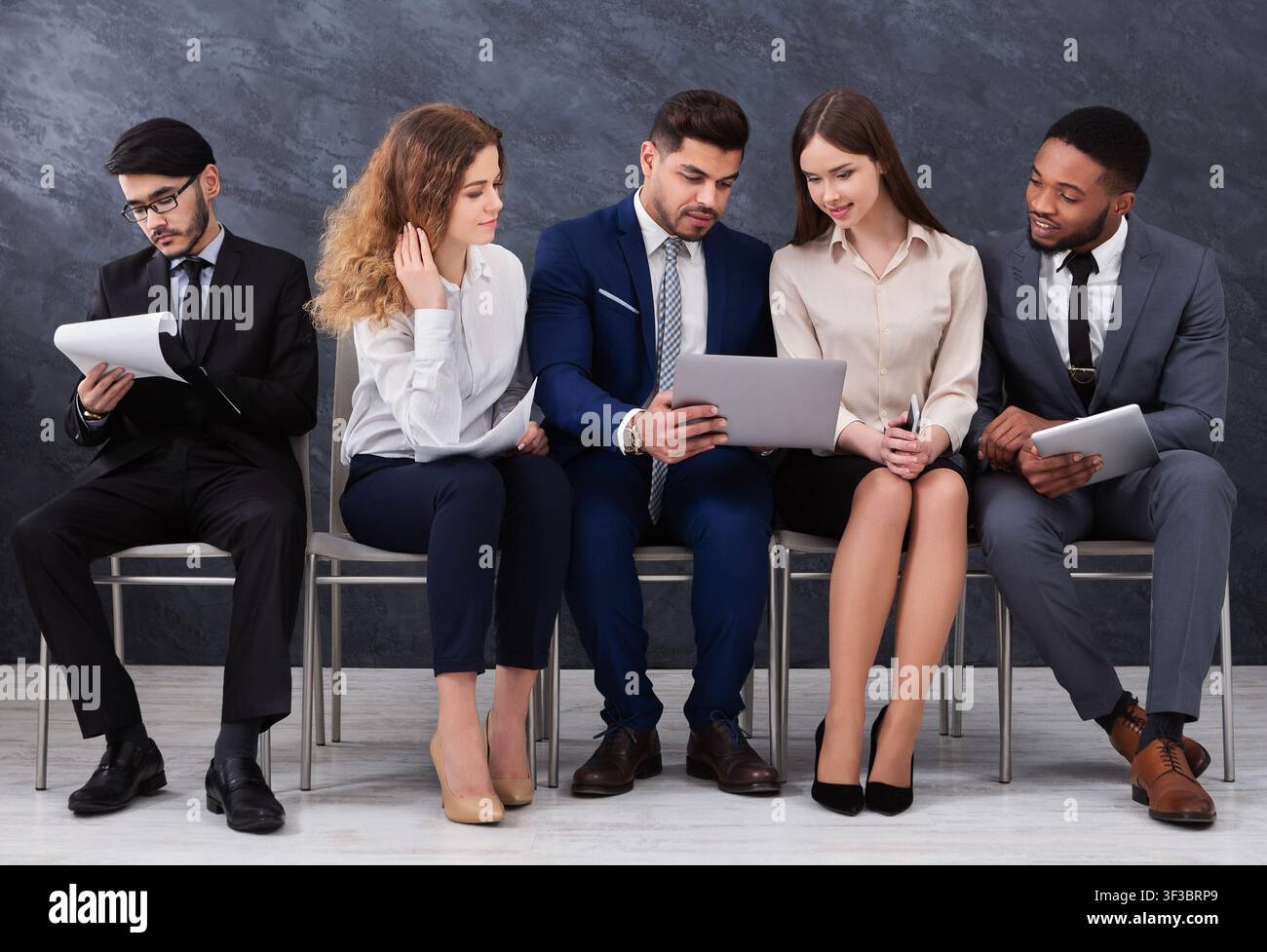 Diverse young businesspeople using laptops and smartphones Stock Photo