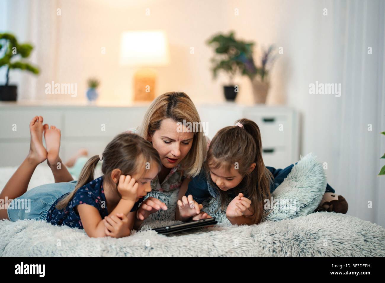 Mother and children using digital tablet in bed Stock Photo