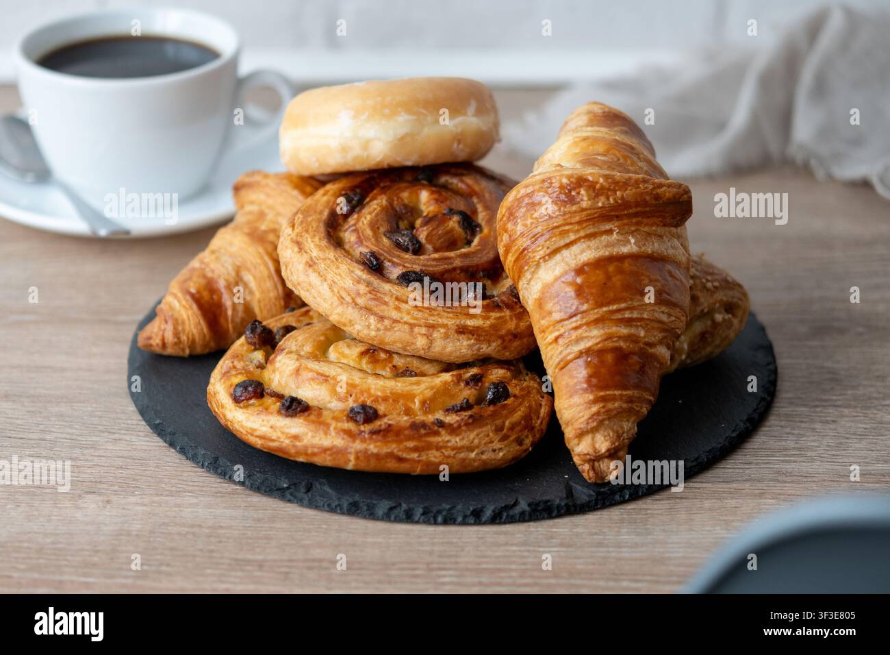 Assorted breakfast pastries with black coffee on wooden table Stock Photo