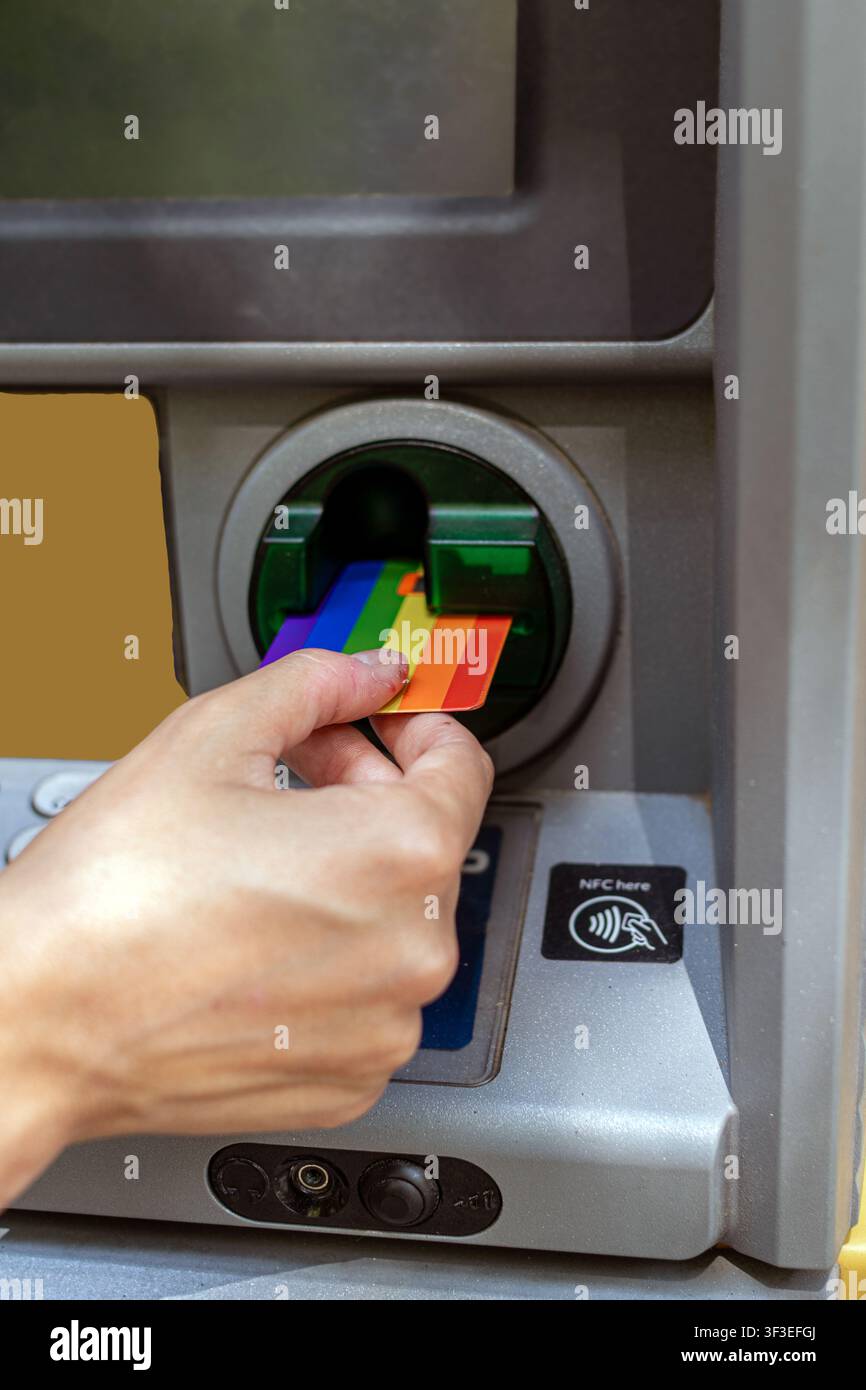 Hand inserting rainbow credit card into an atm Stock Photo