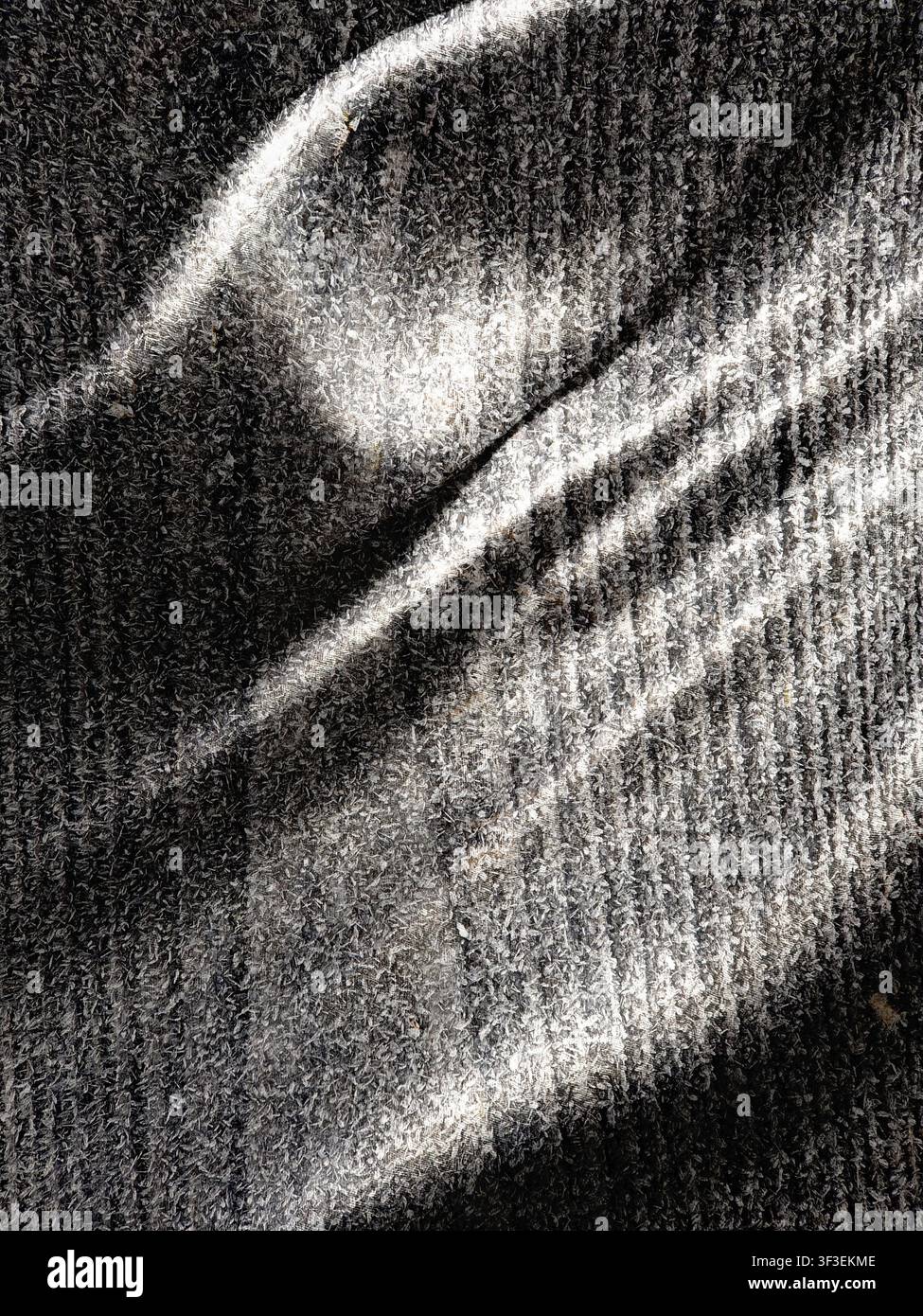 This image features a textured grey surface dramatically illuminated by strong diagonal light and shadow patterns Stock Photo