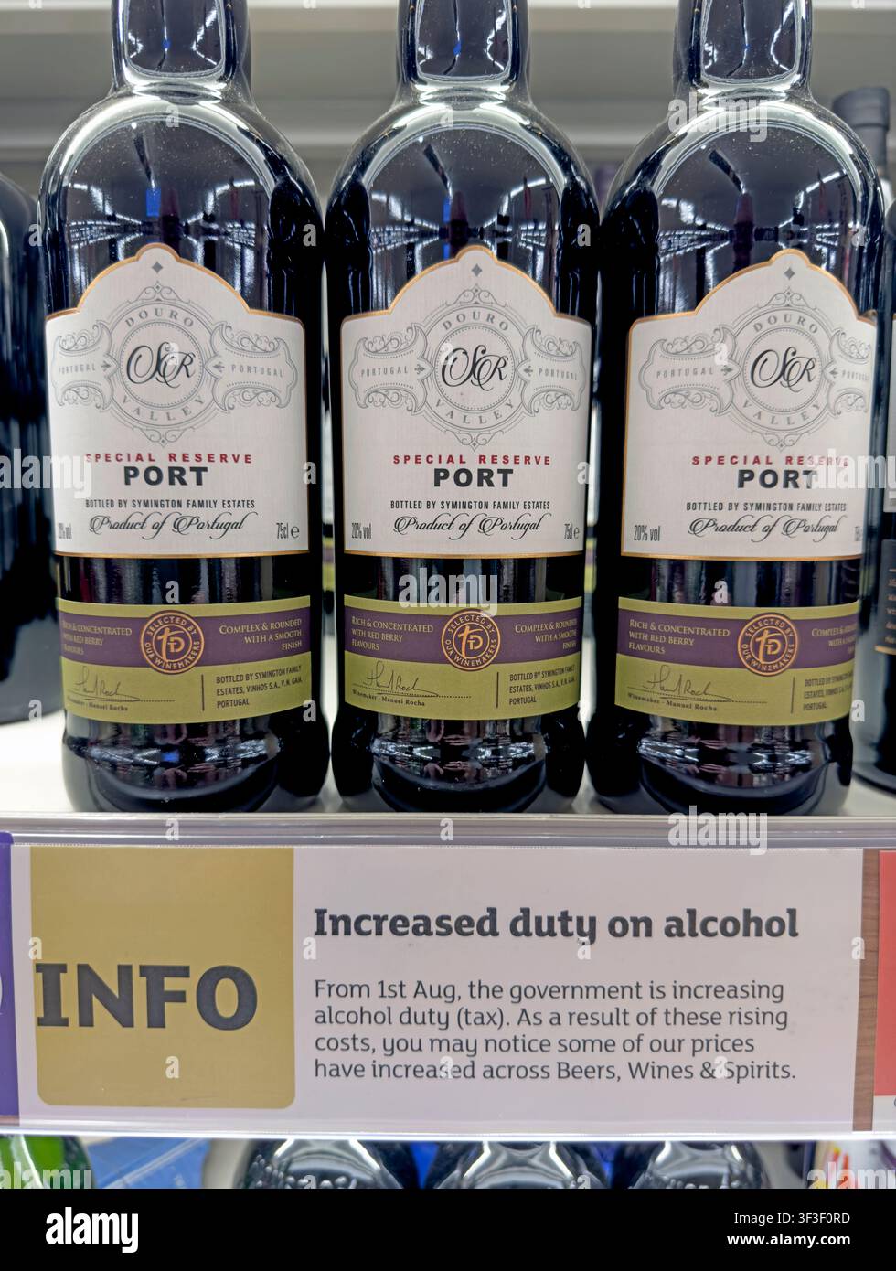 Port wine bottles beside an information sign about increased duty on alcohol, photographed in Britain. Stock Photo