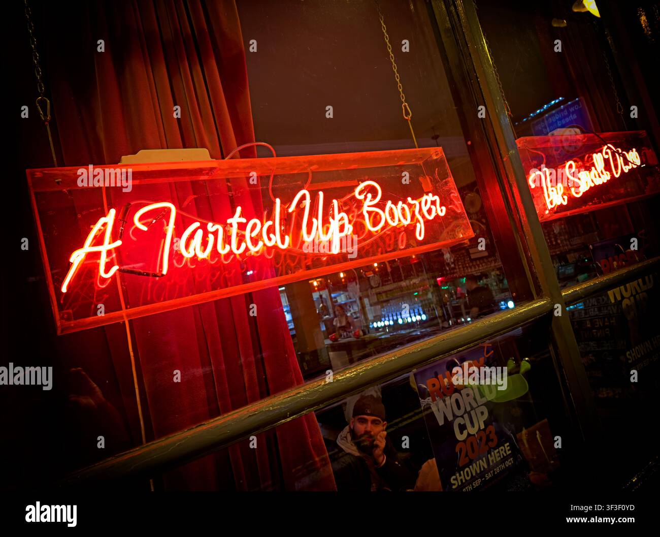 A Tarted Up Boozer neon sign glowing in the window of a Hackney London pub, The Star England, UK. Stock Photo