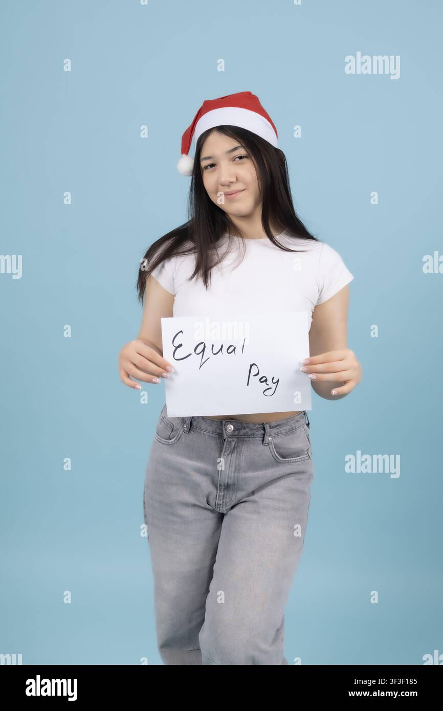 Young woman wearing santa hat holding white sign board studio Stock Photo