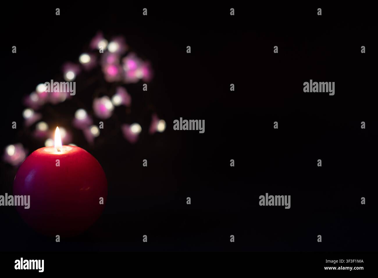 Red candle with festive bokeh lights on dark background, celebration concept with copy space Stock Photo