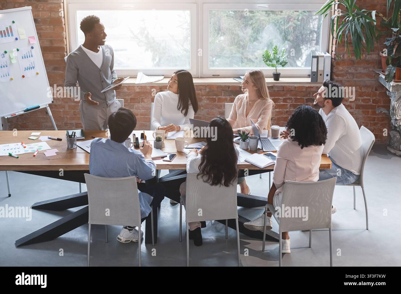 Enthusiastic black guy sharing creative ideas with team Stock Photo