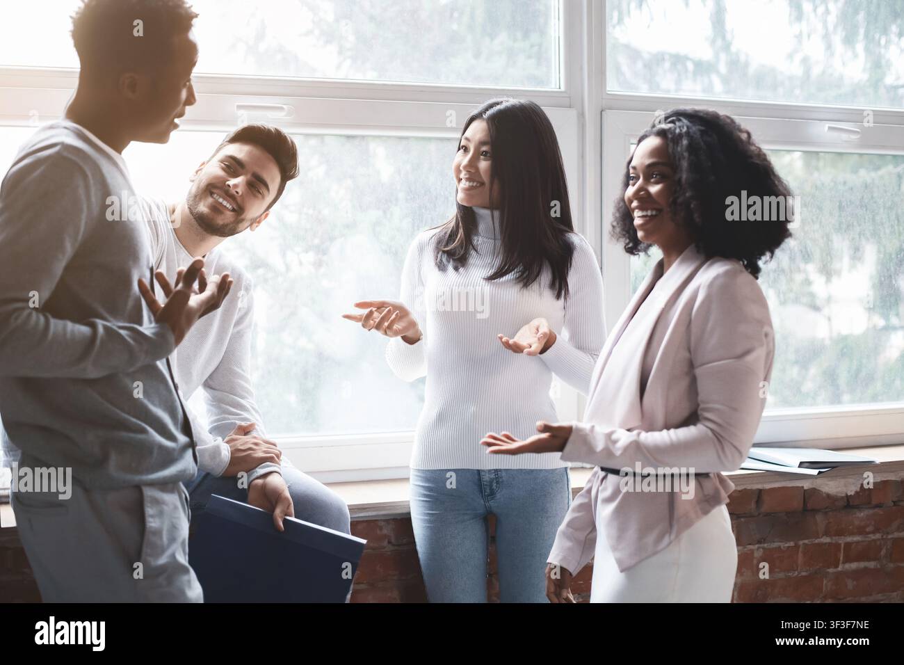 Cheerful multiracial colleagues having small talk in office Stock Photo