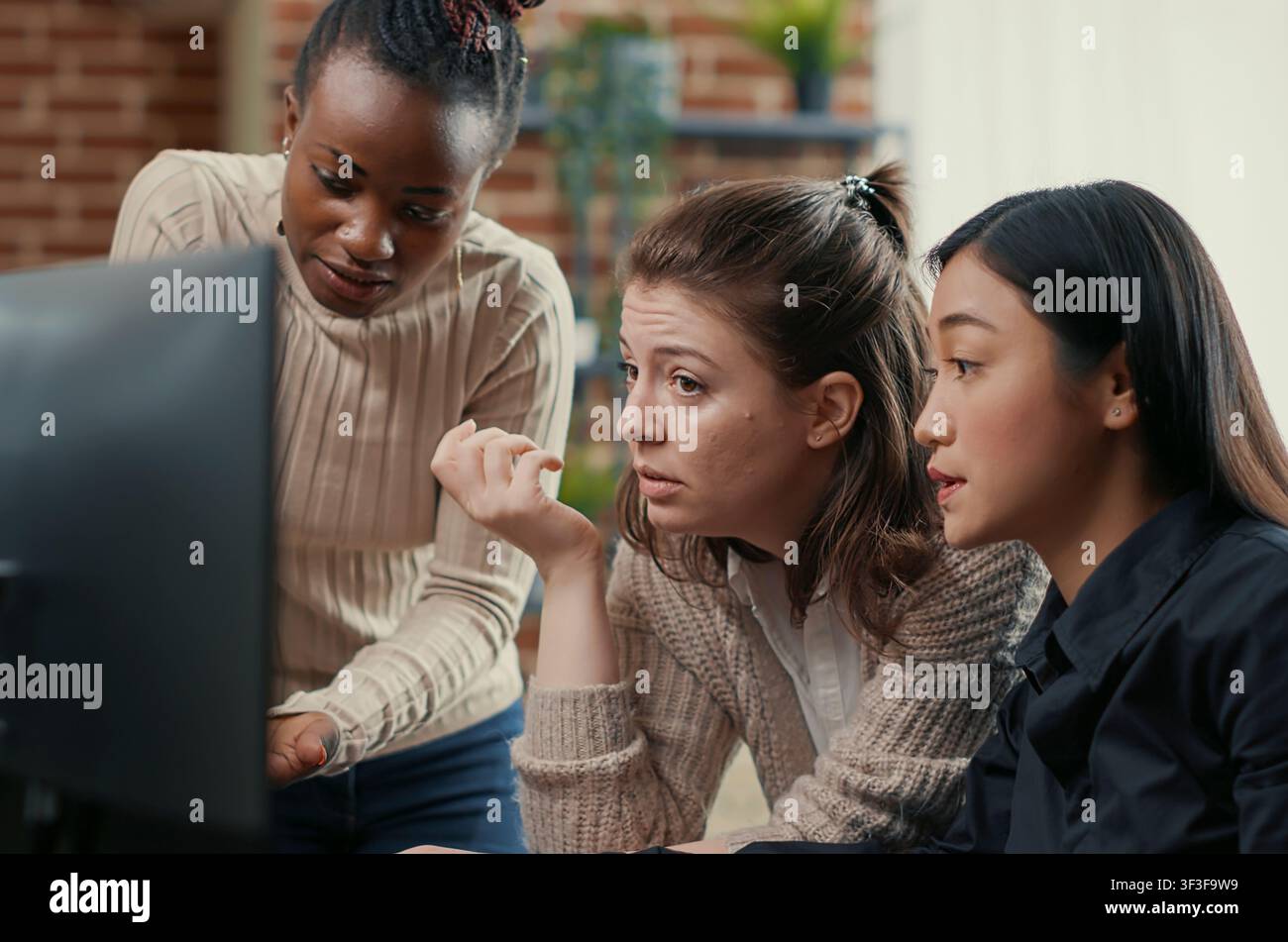 Software engineer points at a computer screen while explaining running code to coworkers, brainstorming software ideas and collaborating on an IT group project. Stock Photo