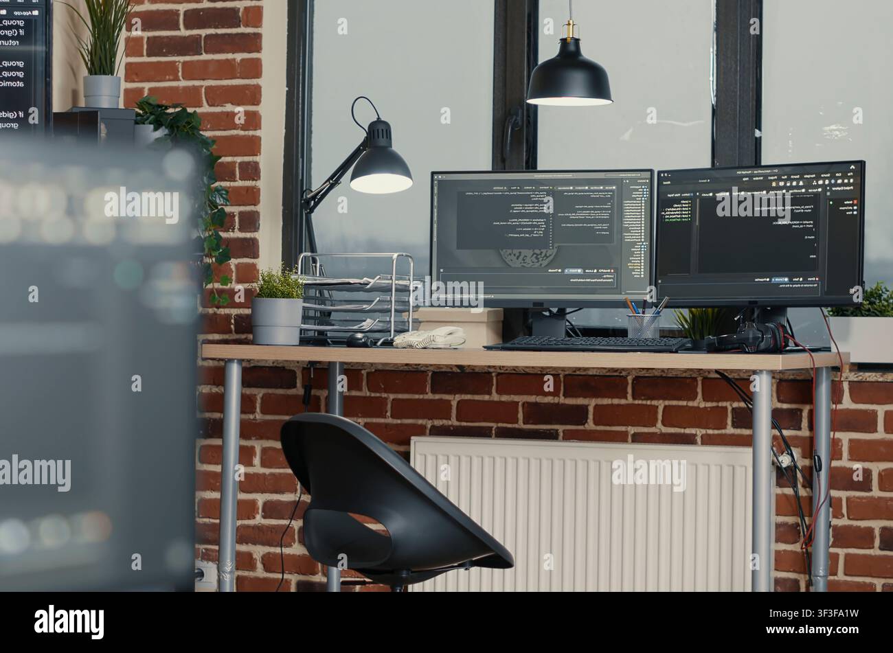 Multiple computer monitors display parsing code and programming language compiling in an empty software development agency office. Stock Photo