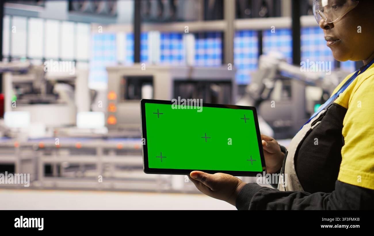 Smart factory specialist using green screen tablet to test automated systems to ensure reliability. Industry 4.0 plant technician using chroma key device to identify bottlenecks and optimize, camera A Stock Photo