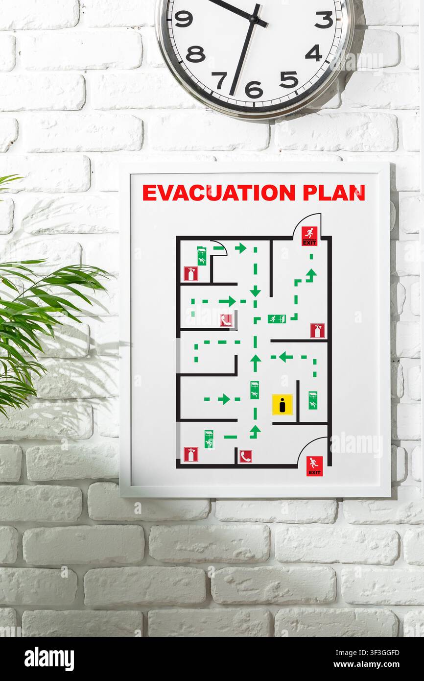 Emergency evacuation plan displayed on wall with clock showing time Stock Photo