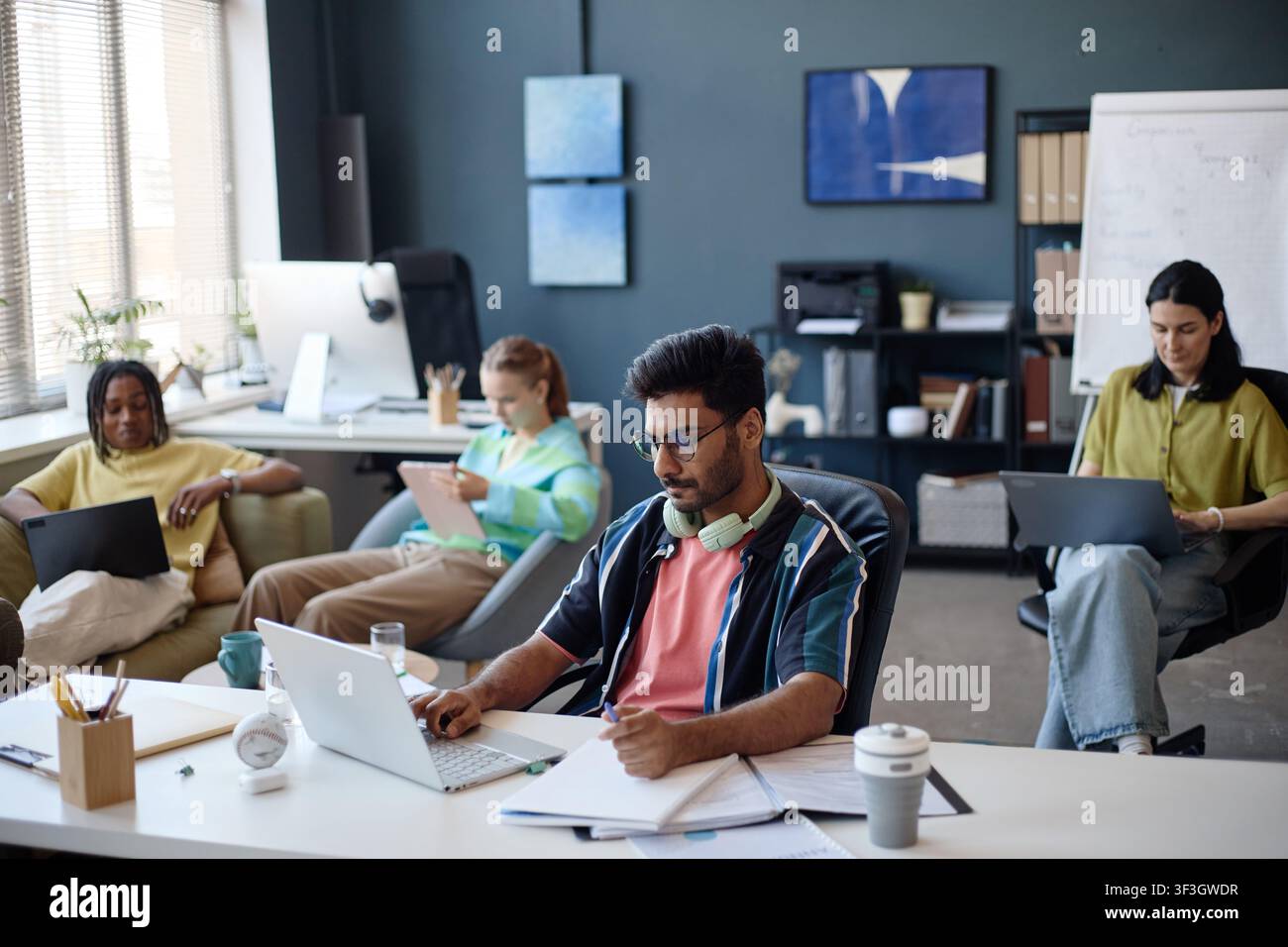 Diverse Coworkers Working on Laptops in Collaborative Office Stock Photo