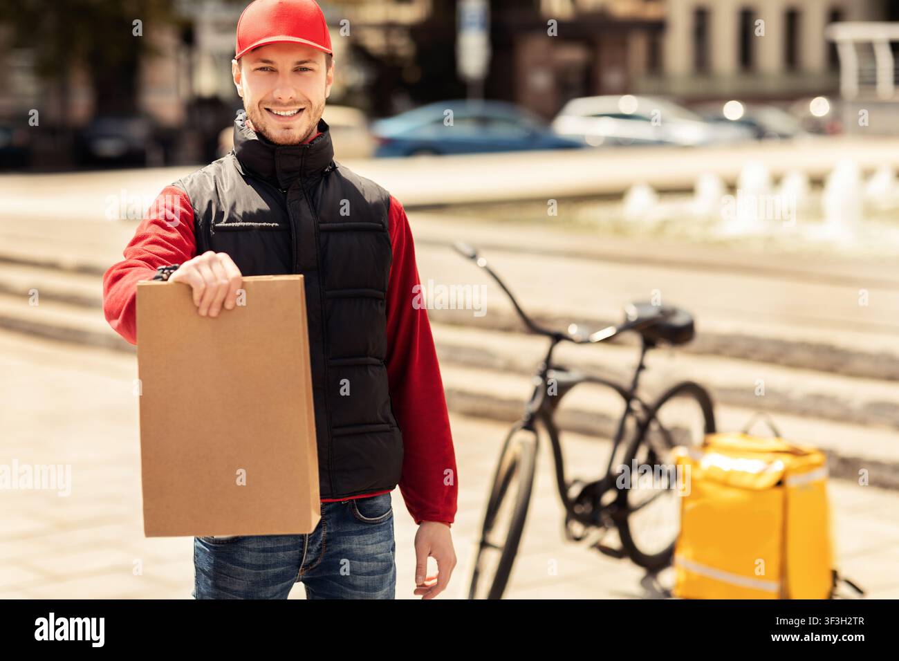 Courier Guy Holding Package Smiling To Camera Standing Outside Stock Photo