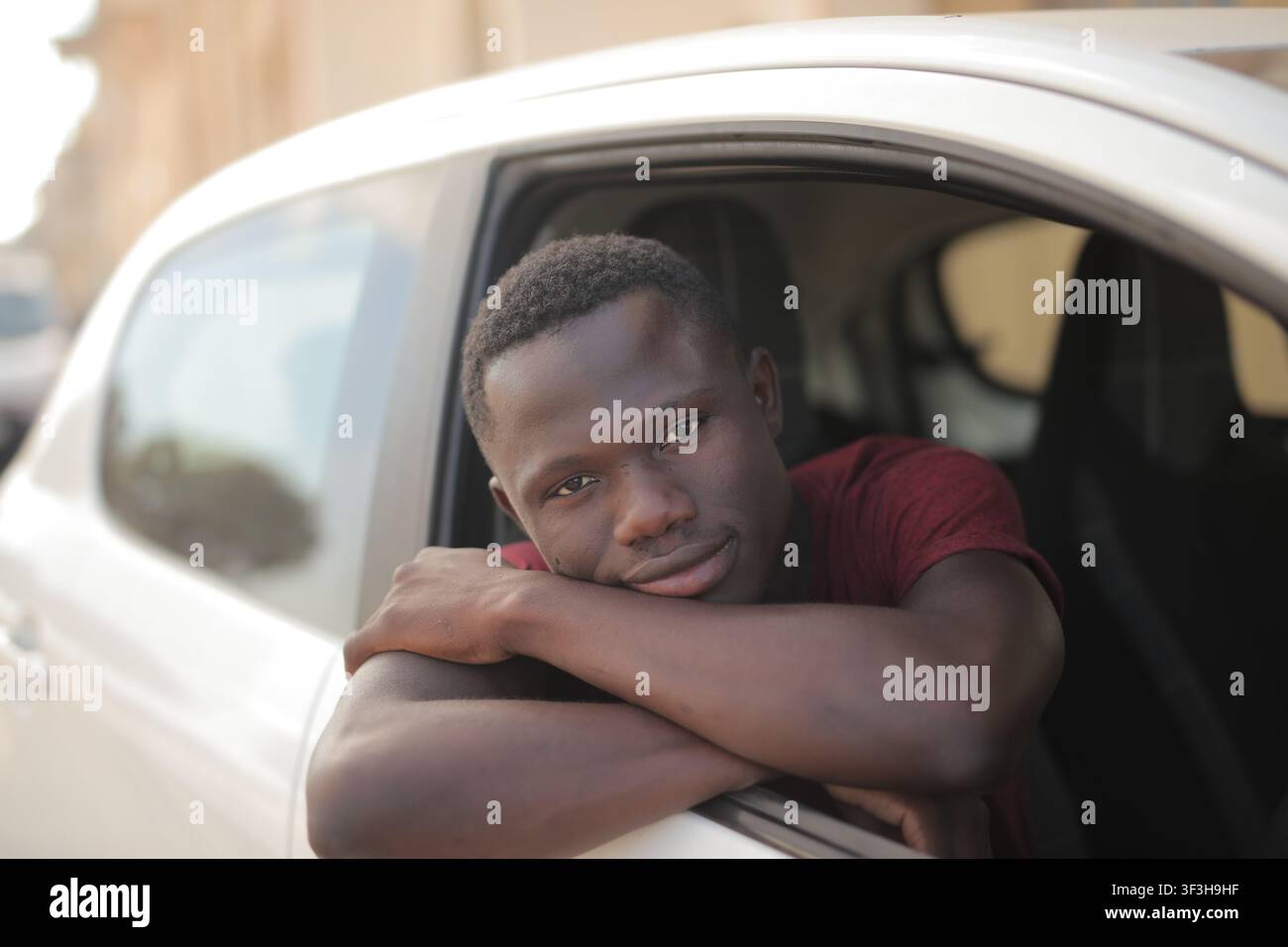 Young man smiles while leaning out his car window Stock Photo