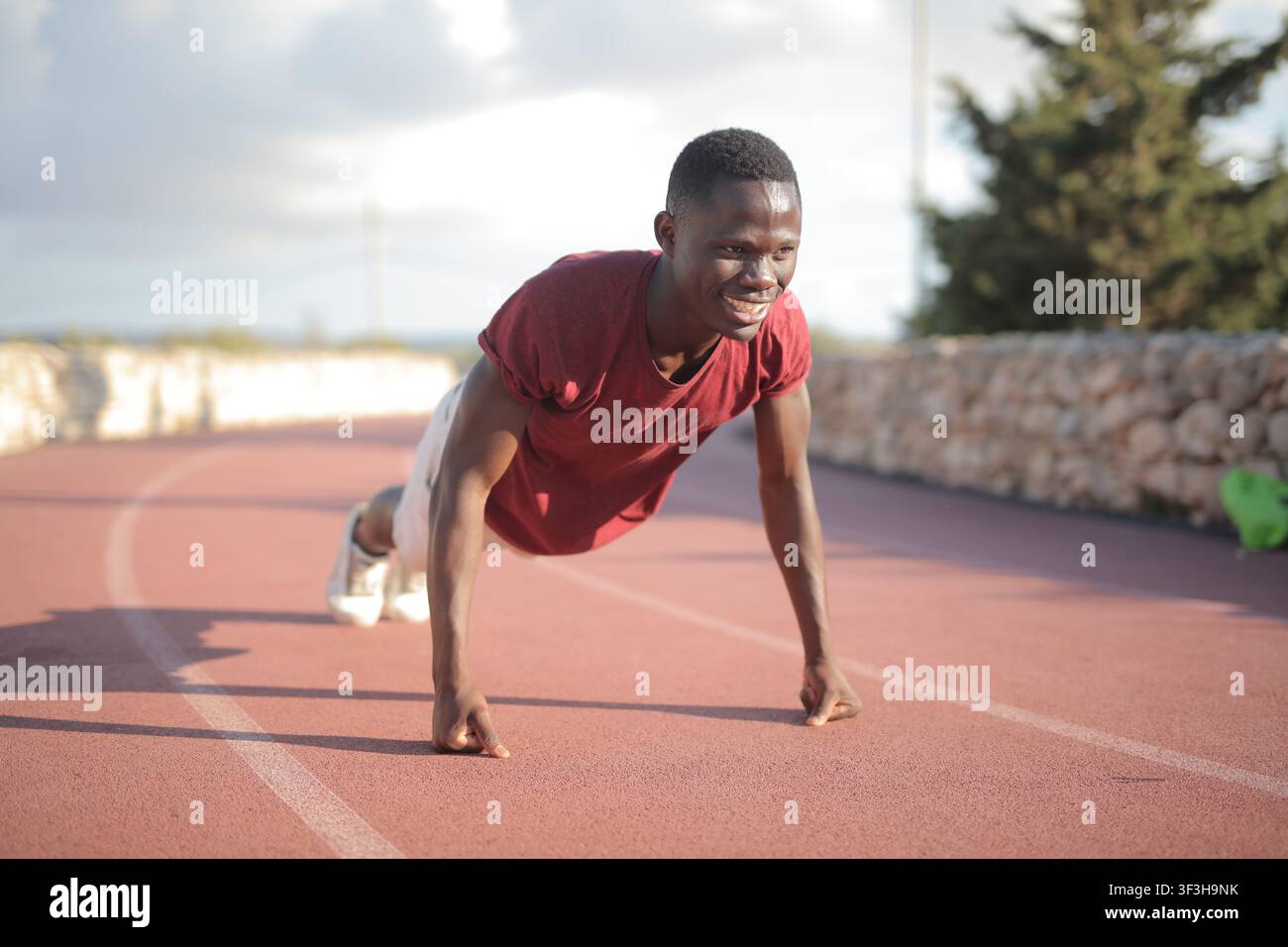 Young Black man smiling while doing pushups outdoors Stock Photo