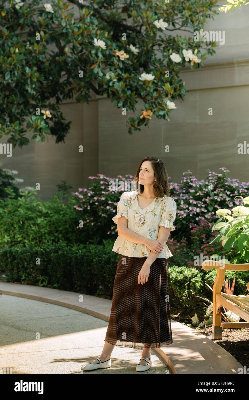 Thoughtful woman standing under a magnolia tree Stock Photo