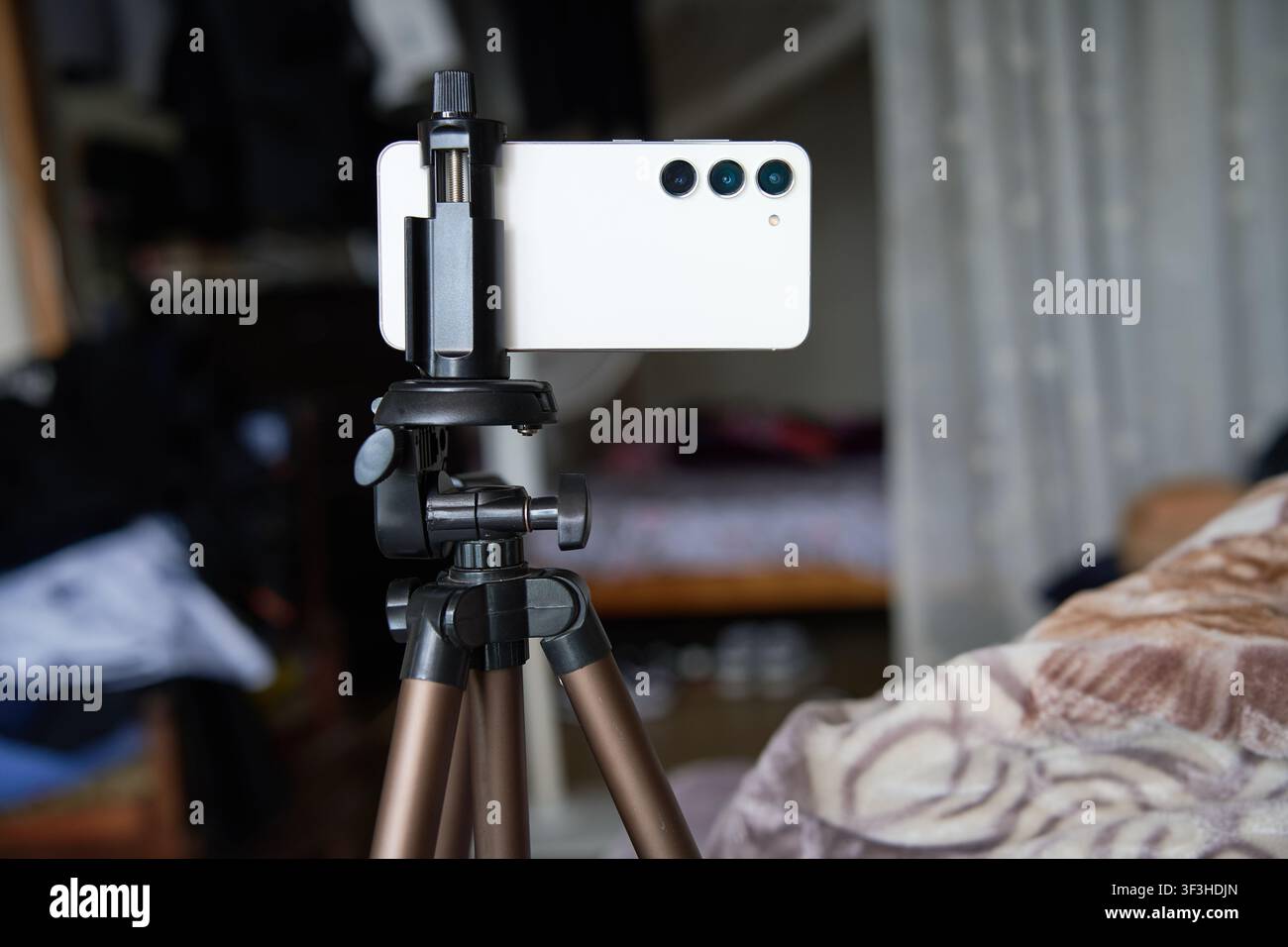 A white smartphone mounted on a mobile tripod with soft blur background Stock Photo
