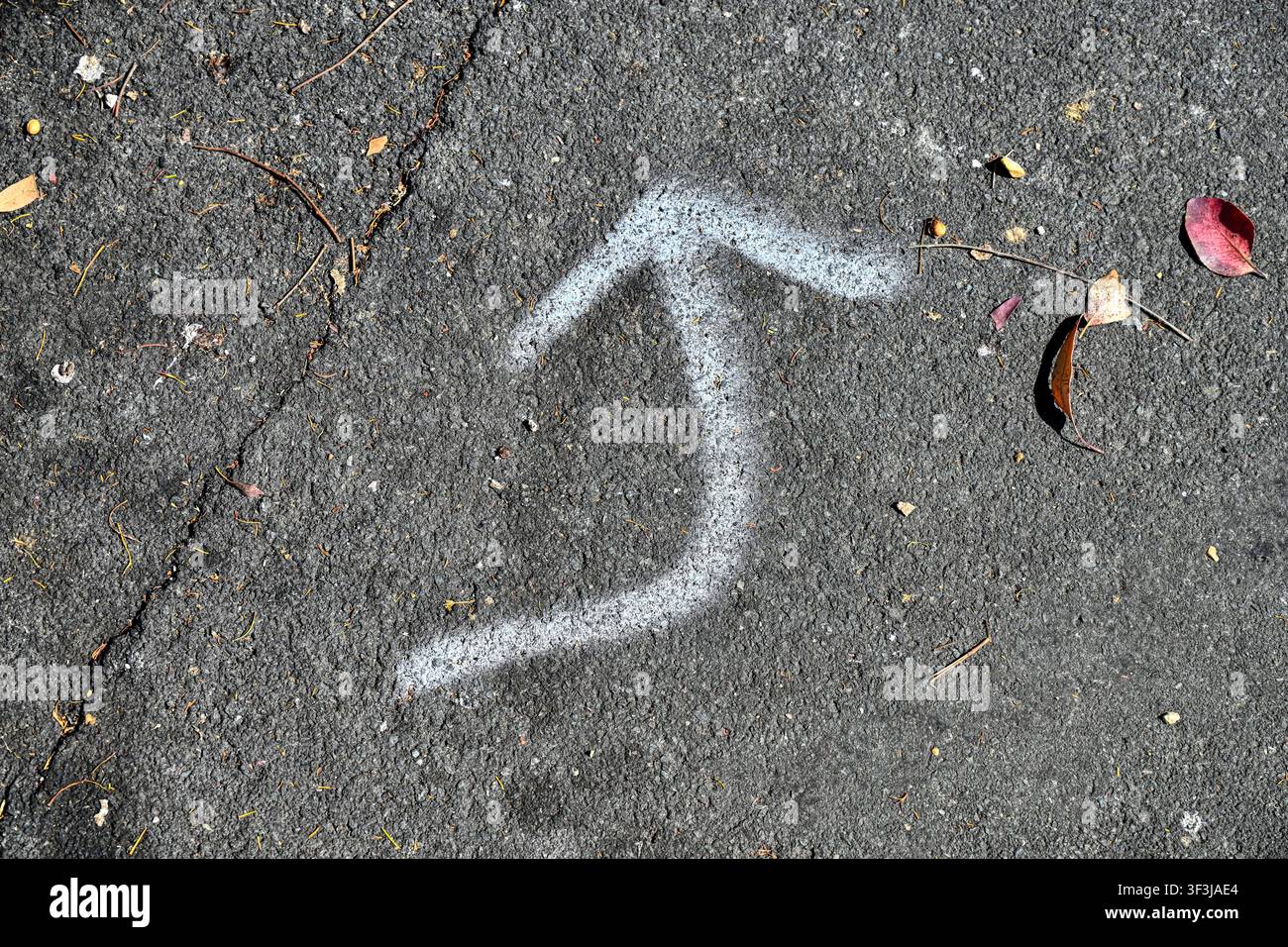 Bent arrow sprayed on path using white paint Stock Photo