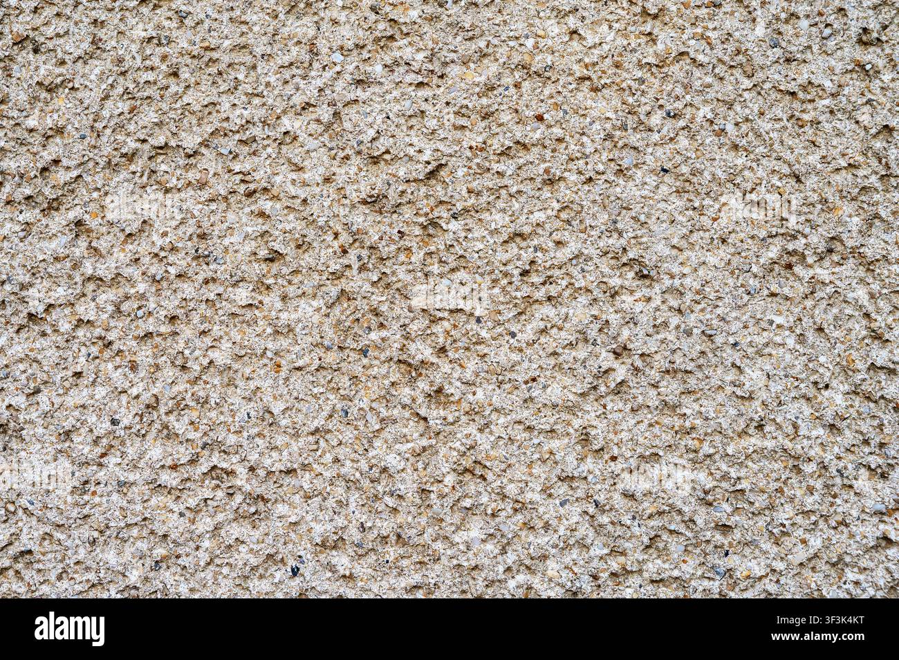 Rough exposed aggregate concrete wall texture with granular surface. Stock Photo