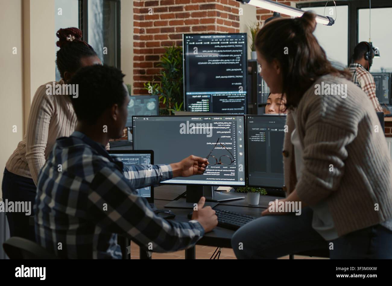 Programmer sits on a desk and discusses artificial intelligence innovation with a mixed team reviewing machine learning algorithms. Stock Photo
