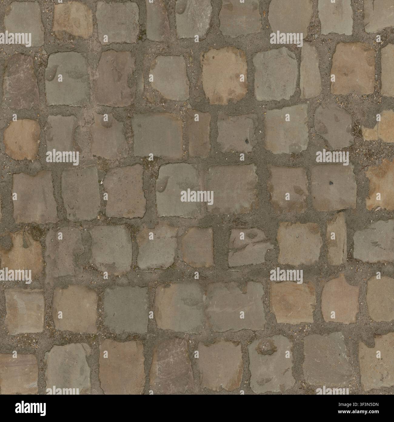 A top-down view of grey stone cobblestones arranged in a traditional outdoor paving pattern. Stock Photo