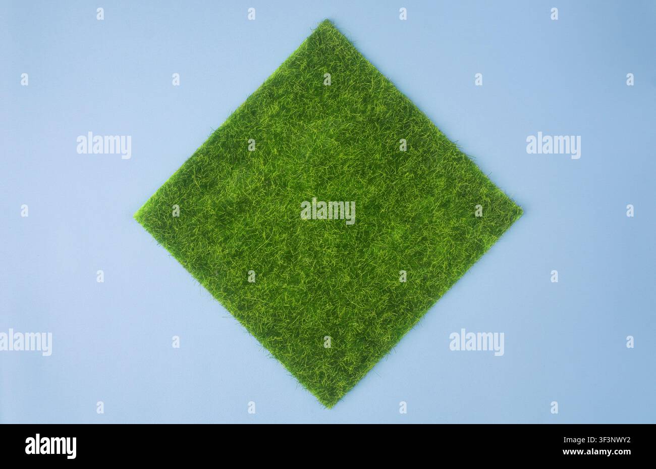 Square Green Grass Patch on Blue Background Top View Stock Photo