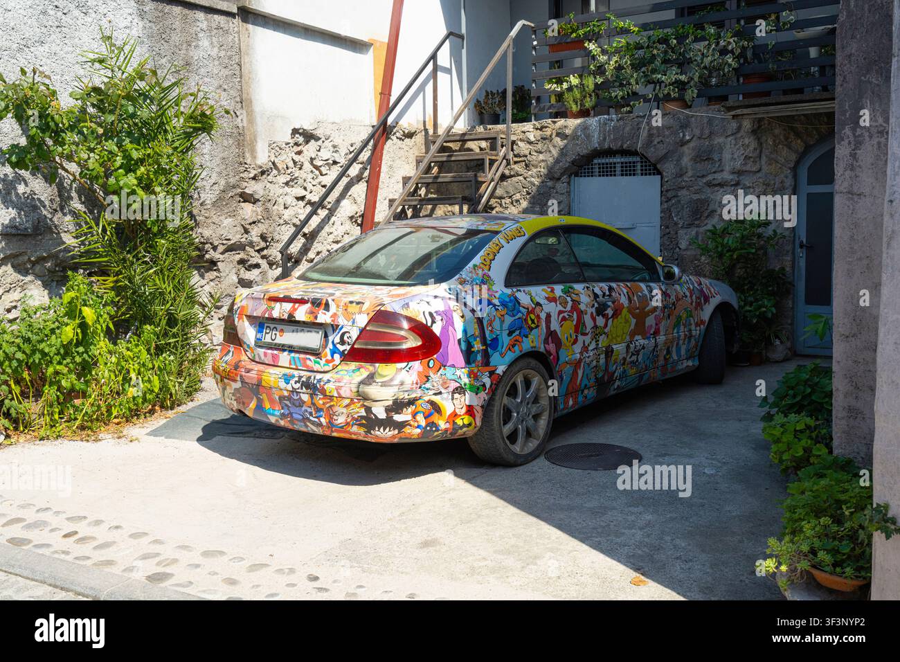 Podgorica, Montenegro. July 20, 2026. A car is covered in a colorful, intricate decal wrap featuring numerous cartoon characters. The vehicle is parke Stock Photo