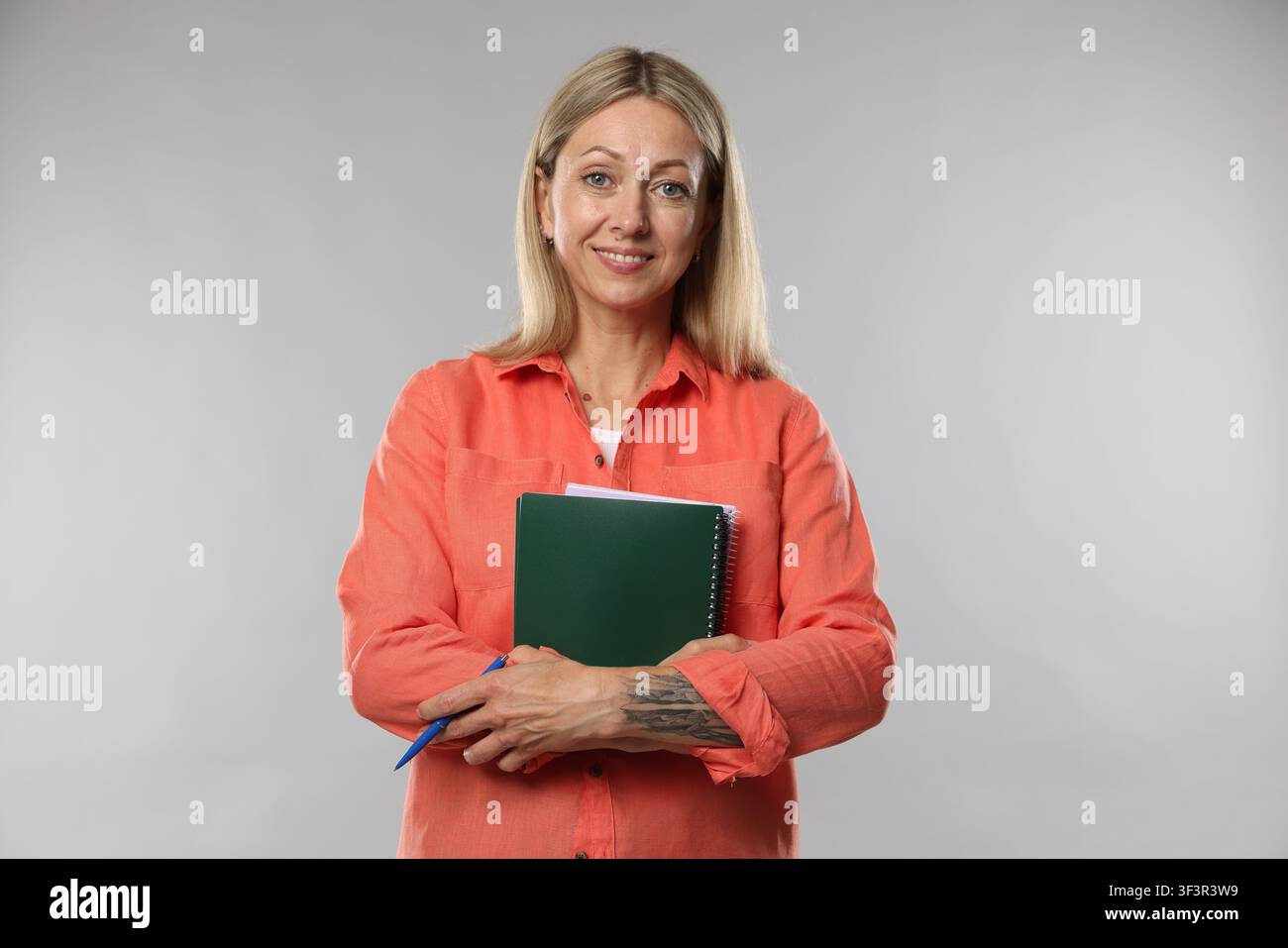 Teacher with notebooks and pen on light grey background Stock Photo