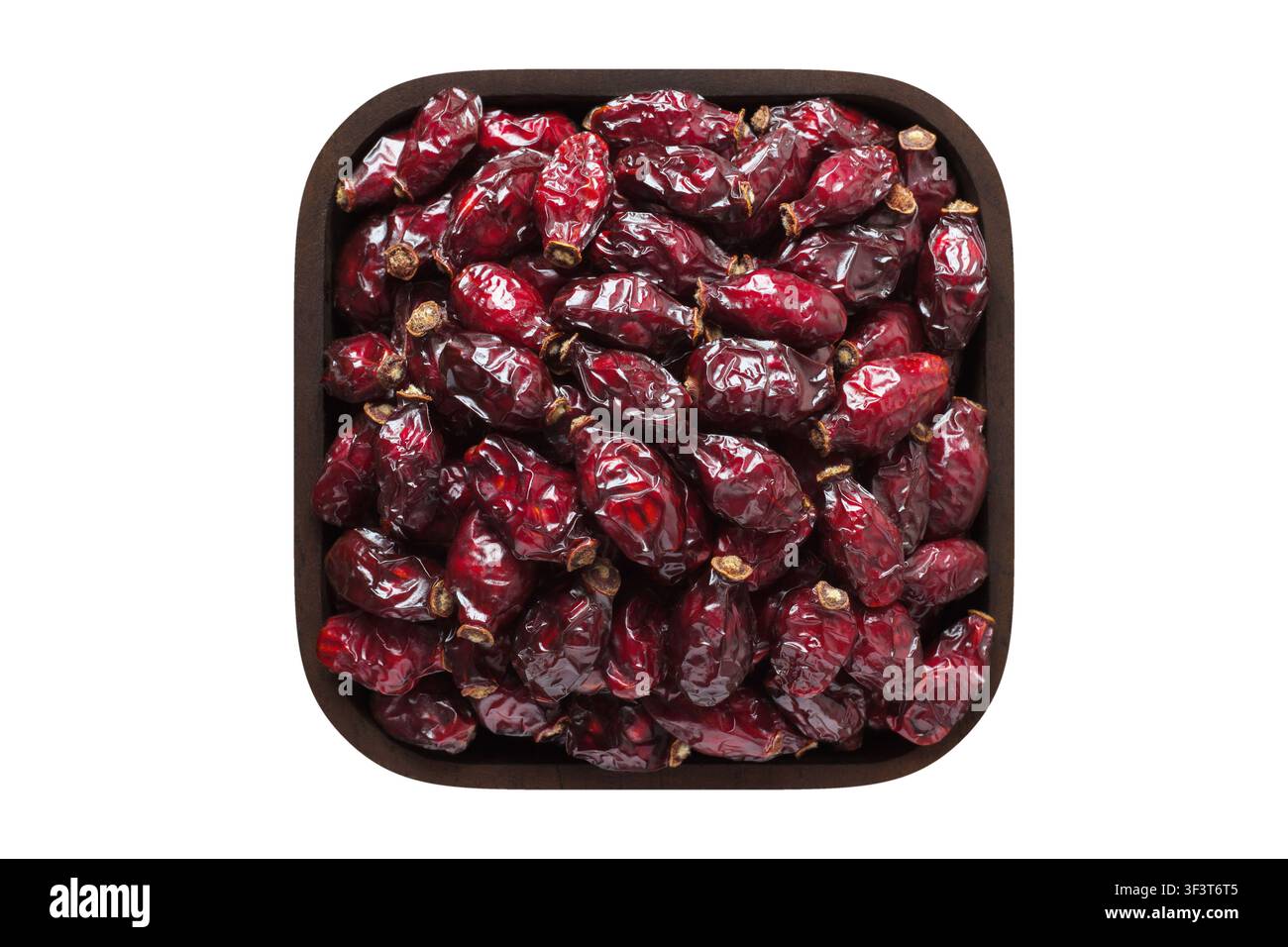 dried rose hips or dogrose berries in wooden bowl closeup. vegetarian food isolated on white. Stock Photo