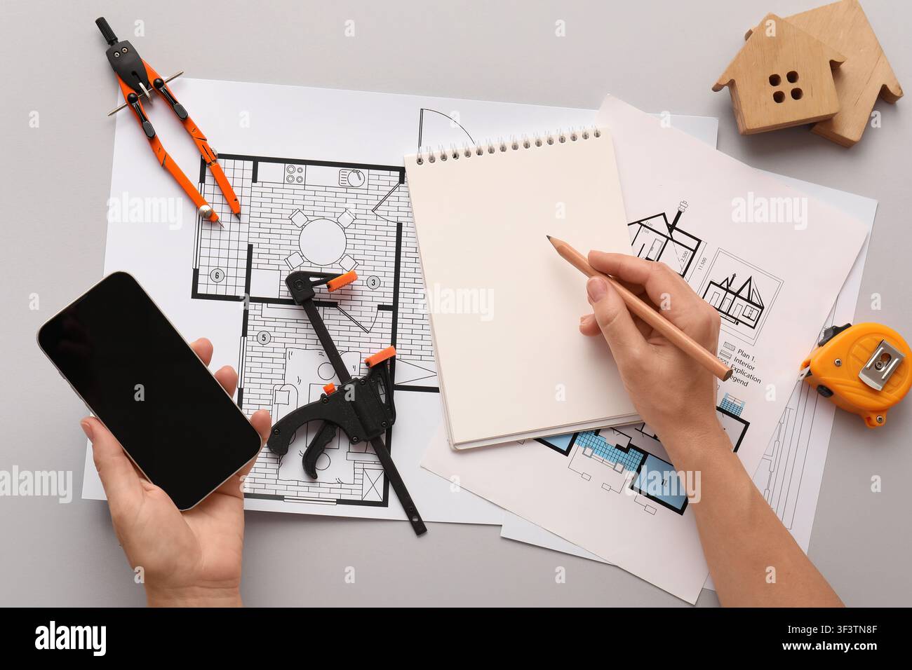 Architectural design process with blueprints, smartphone, and construction tools on a gray background, top view Stock Photo