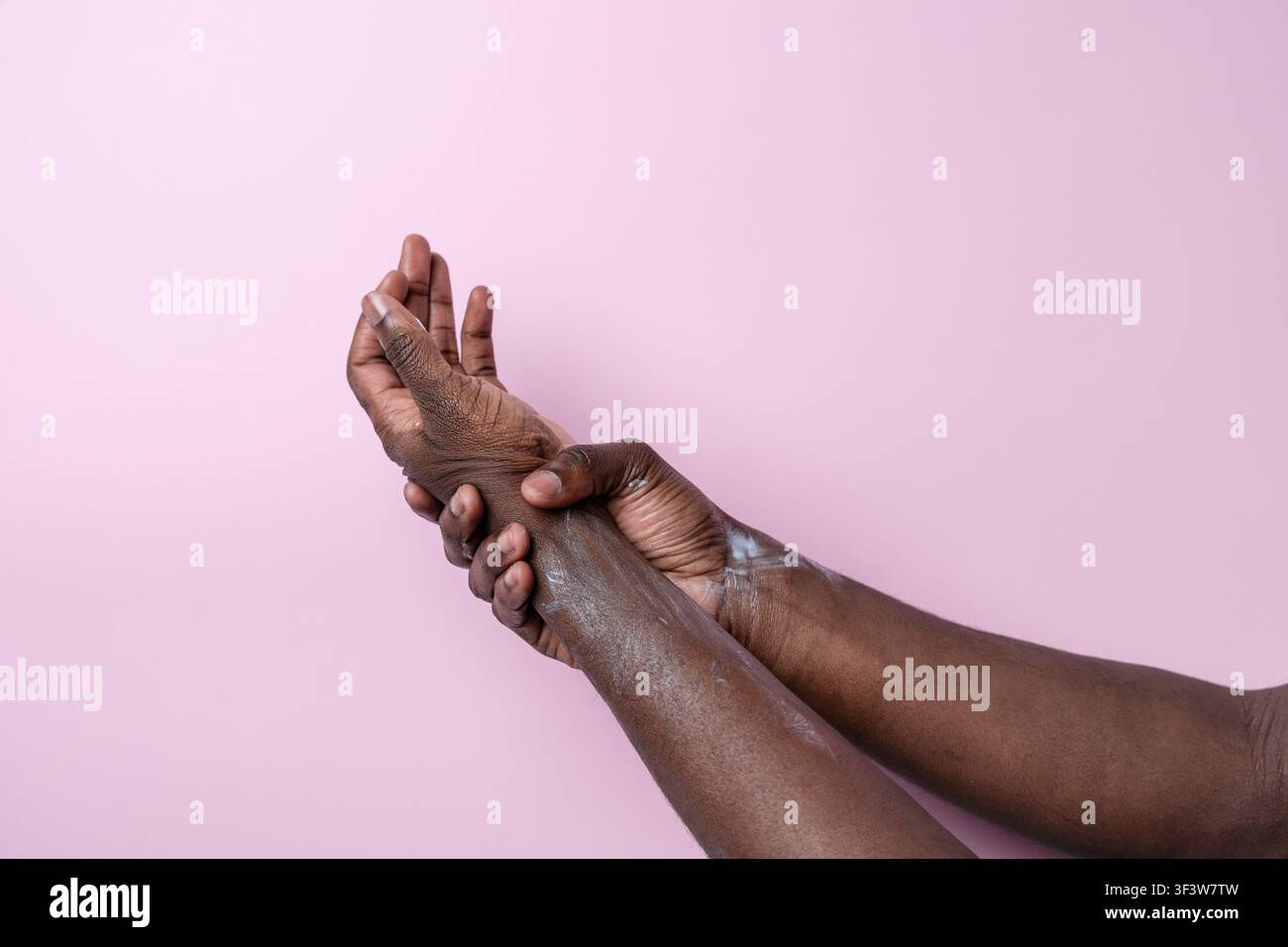 Close-up of a black mans hands gripping his wrist, showing pain and discomfort. Concept of injury, strain, arthritis, or carpal tunnel with copy space Stock Photo