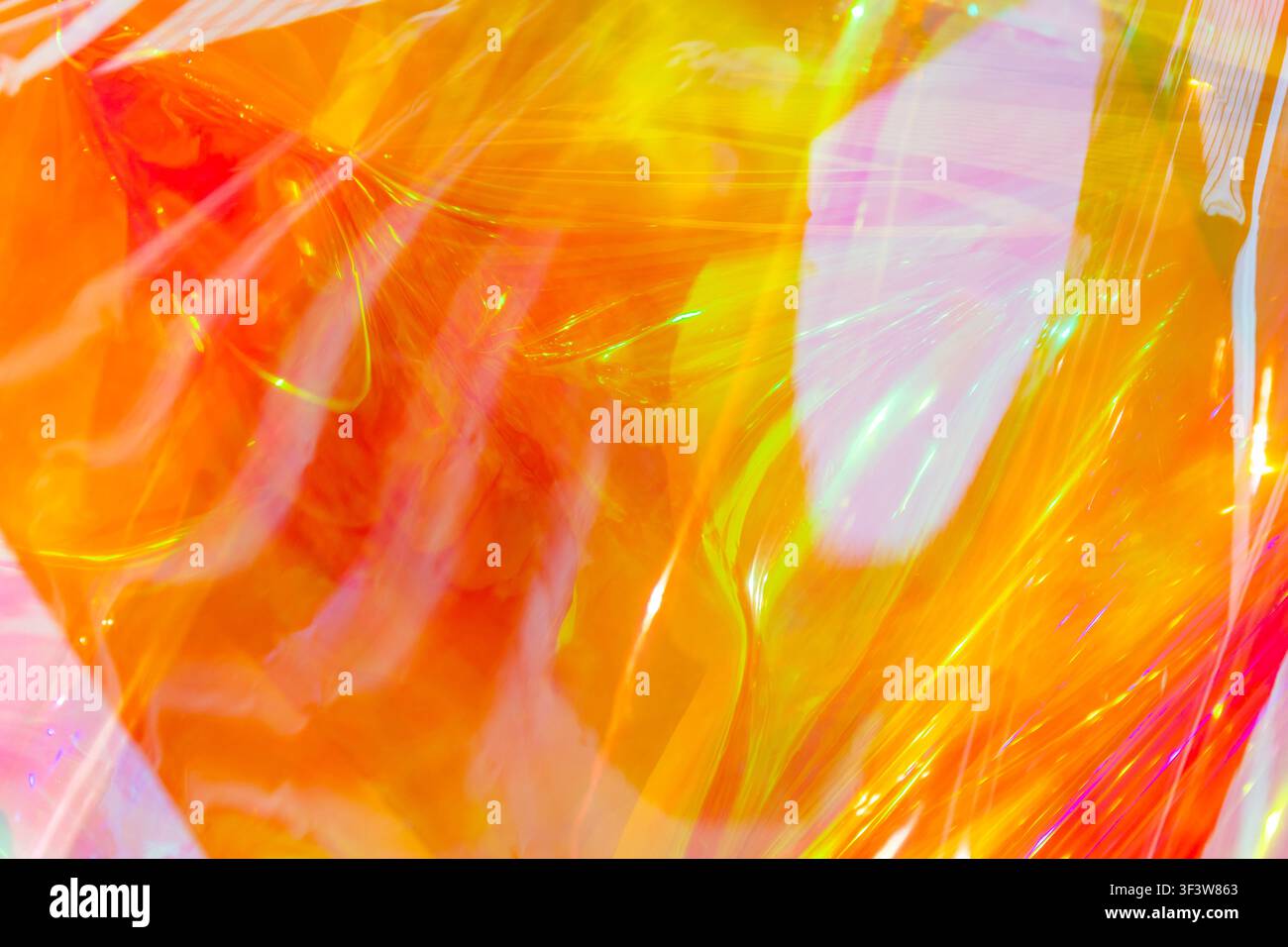 Abstract image featuring vibrant holographic waves in shades of orange, yellow, and pink. The bright, shiny surface resembles a flowing rainbow with d Stock Photo