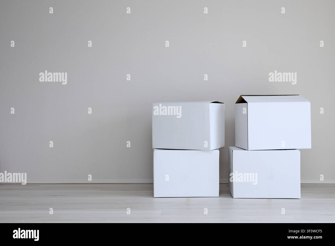 White cardboard boxes stacked against a wall in a bright room Stock Photo