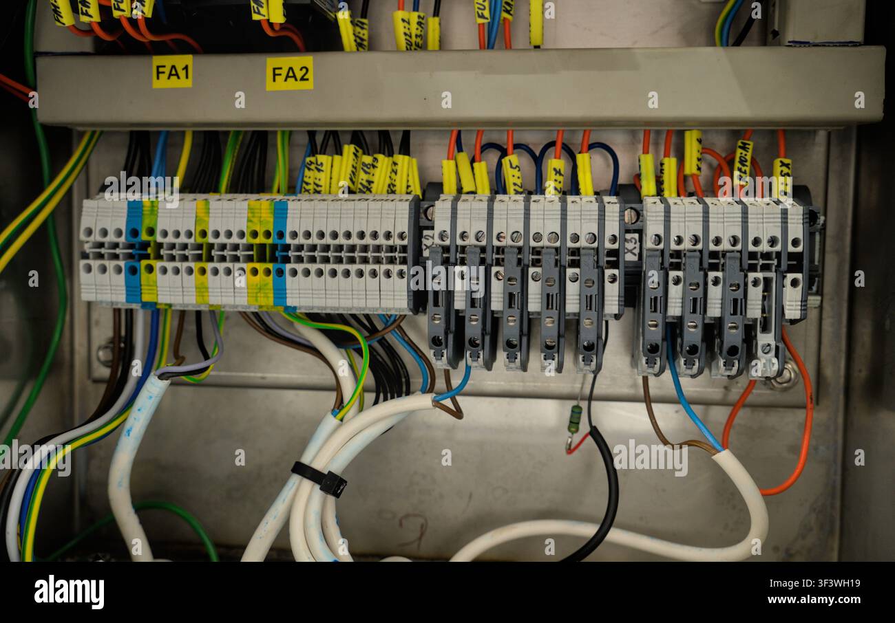 Industrial electrical control panel with terminal blocks and wiring inside a machine cabinet. Stock Photo